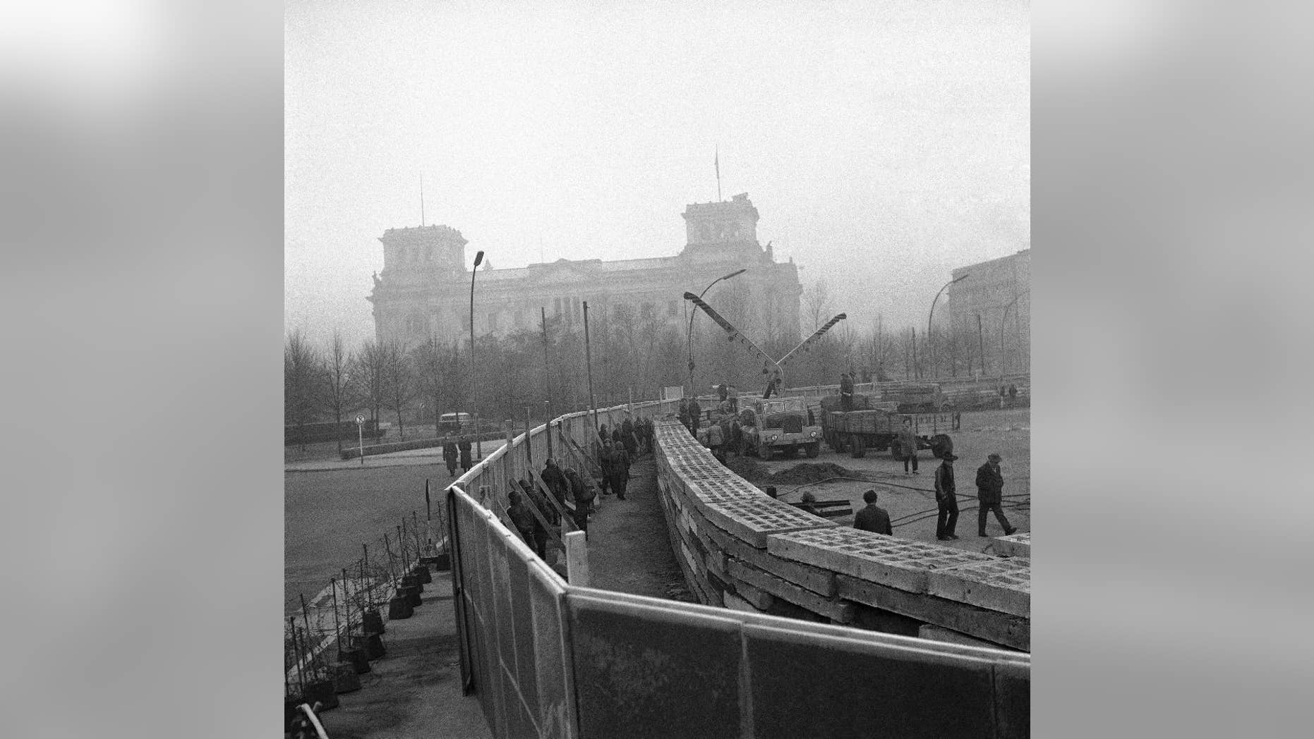 FILE - The Nov. 20, 1961 photo shows 12 feet high boards hiding the work as East German troops erect a new concrete wall at the Brandenburg Gate, marking the East-West border in Berlin. In background is the former Reichstag building which is in West Berlin. (AP Photo/file)