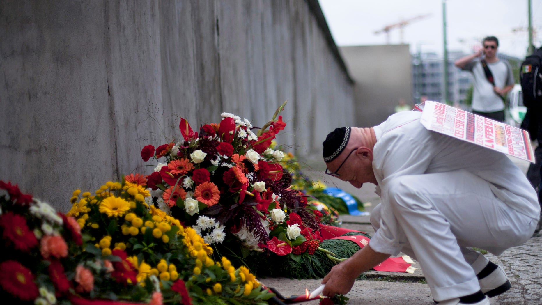 Achim von Almrich lights a candle at the Berlin Wall Memorial at Bernauer Strasse in Berlin, Saturday, Aug. 13, 2011.