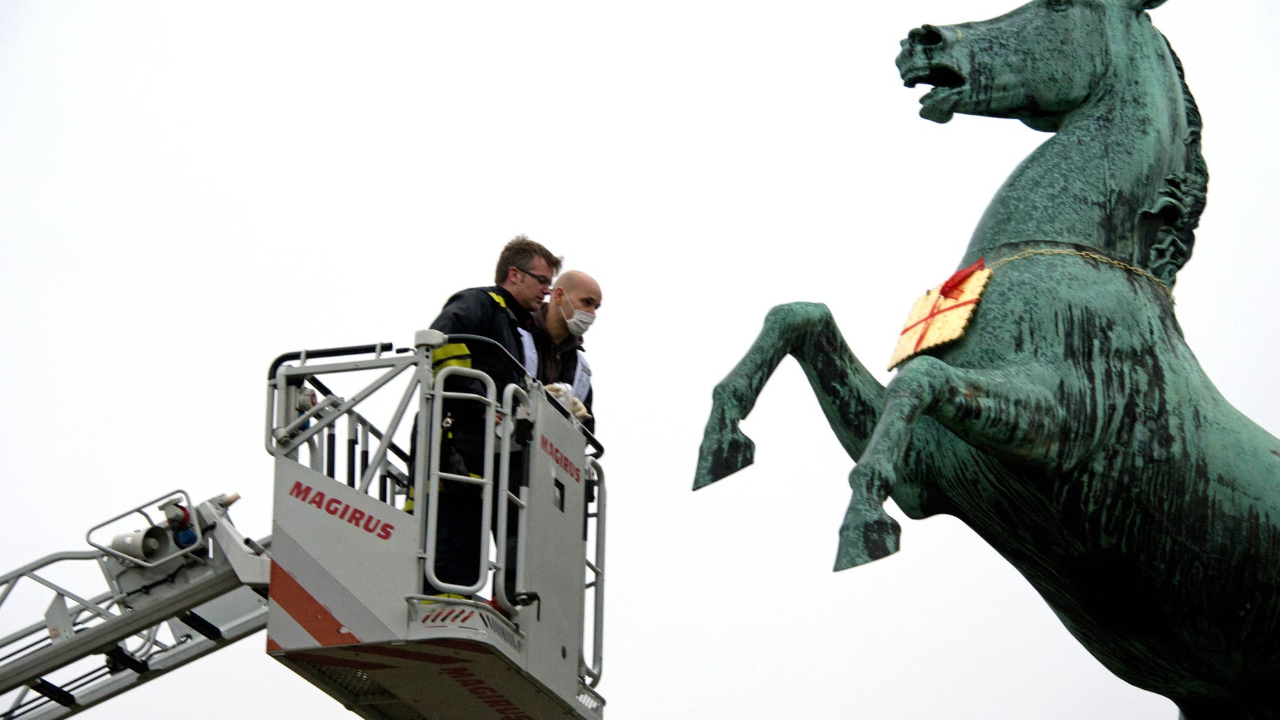Feb. 5, 2013: A firefighter and a police officer look at a golden Leibniz cookie that hangs from a horses neck in front of the Leibniz University in Hannover, Germany.