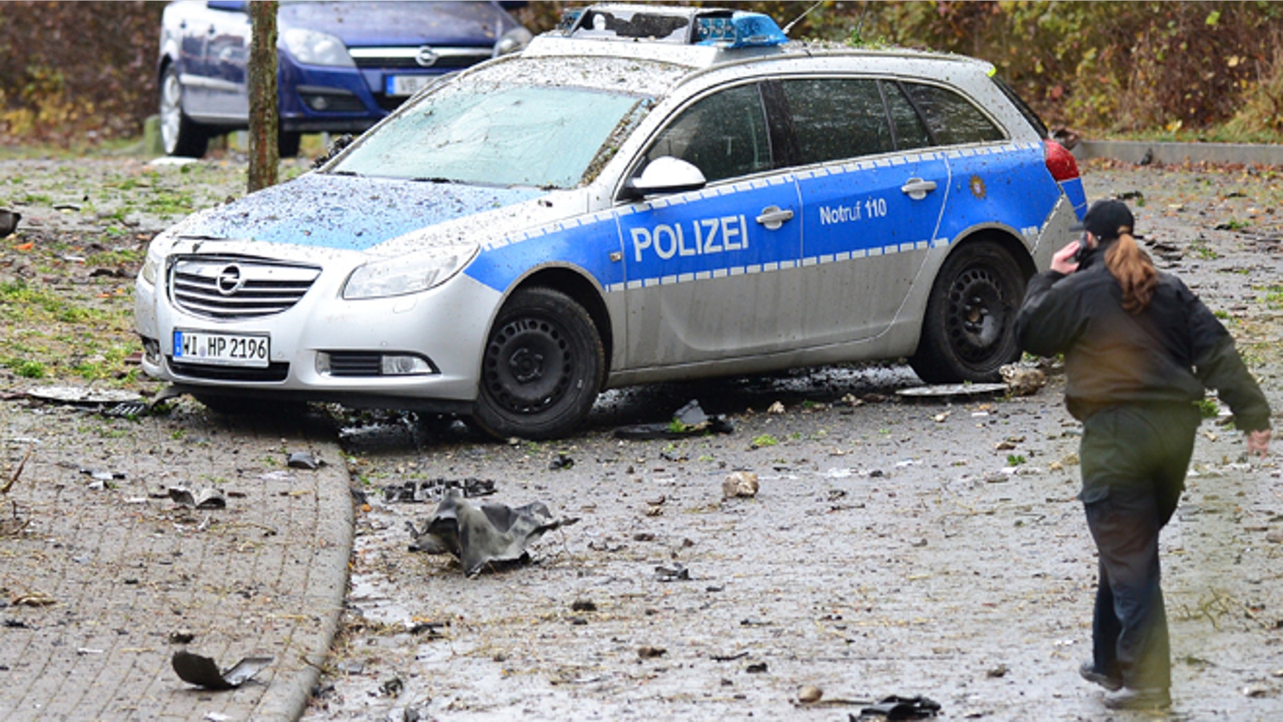 Nov. 16, 2014: A police woman passes a destroyed police car near Homberg Germany. (AP/dpa,Boris Roessler)