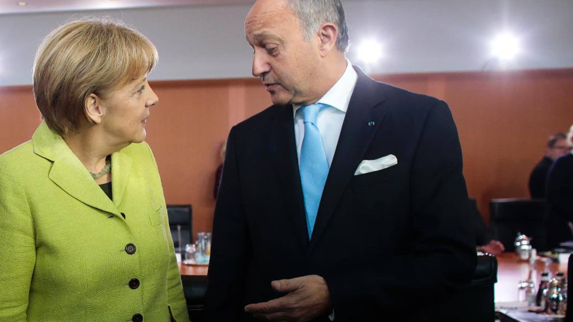 German Chancellor Angela Merkel, left, welcomes France Foreign Minister Laurent Fabius, right, for the German government's cabinet meeting at the chancellery in Berlin, Wednesday, Oct. 15, 2014. Laurent Fabius attends the cabinet meeting as a guest. (AP Photo/Markus Schreiber)