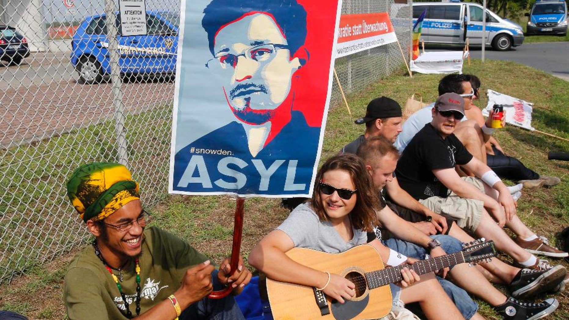 A demonstrator against spying holds a sign asking for asylum for former NSA contractor Edward Snowden outside US Army's 'Dagger Complex' near Griesheim, Germany, Saturday, July 26, 2014. The massively secured property is run by the US Military and supposed to be used by the US intelligence agency NSA (National Security Agency). (AP Photo/Michael Probst)(AP Photo/Michael Probst)