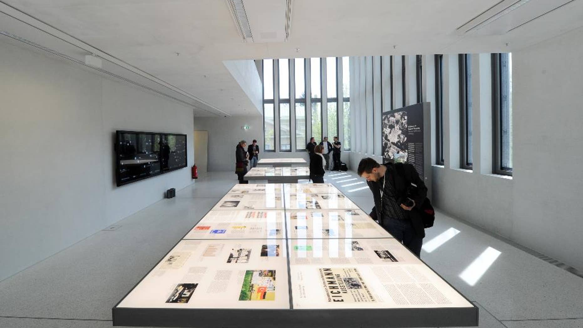 Visitors stand in an exhibition room where exhibits are shown on wall charts and light tables during a press preview of the Documentation Center for the History of National Socialism in Munich, Germany, Wednesday, April 29, 2015. new museum dedicated to exploring its past as the birthplace of the Nazi movement. (Tobias Hase/dpa via AP)