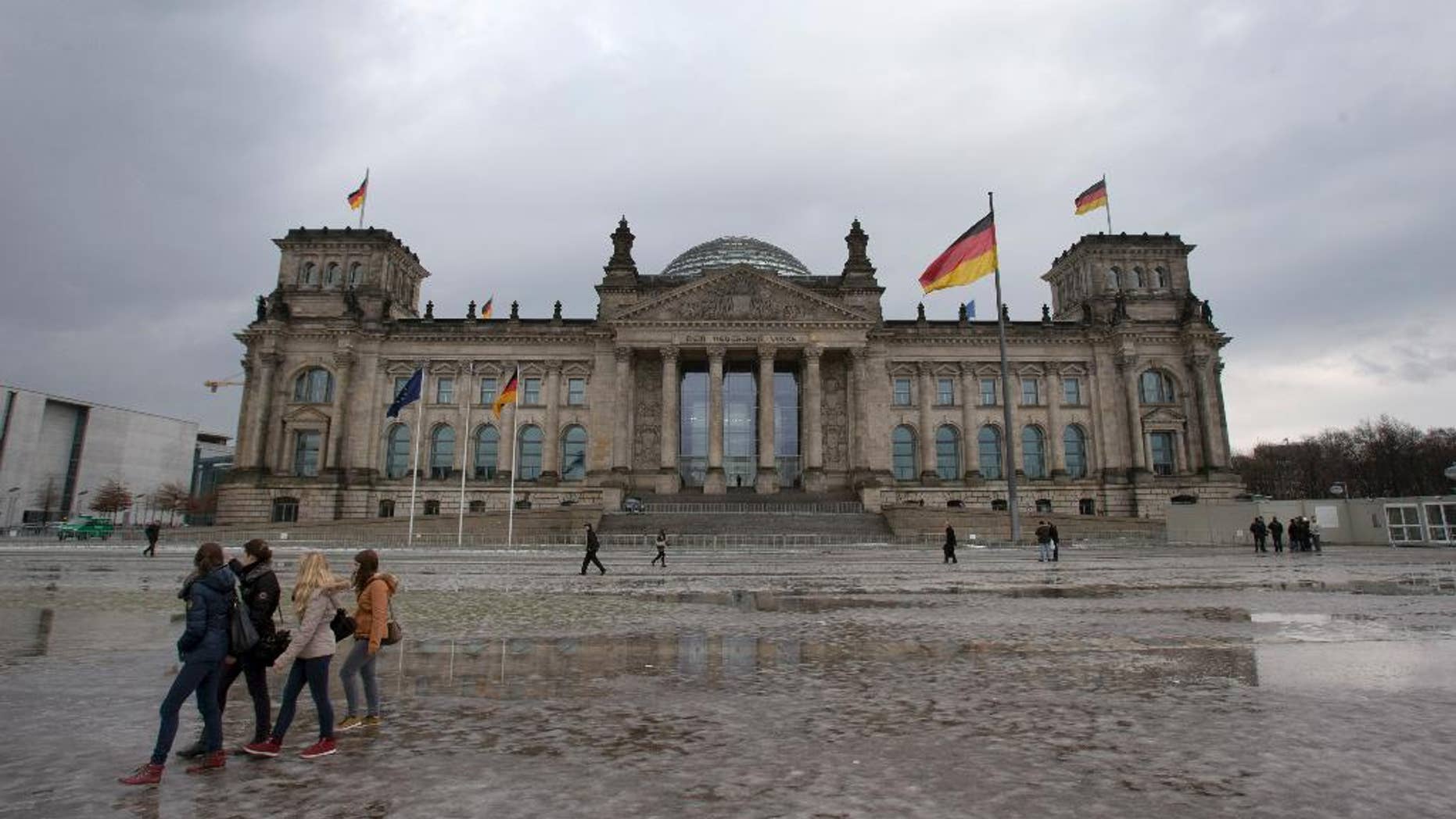 FILE - In this Jan. 29, 2013, file photo visitors walk past the Reichstag building, host of the German federal parliament Bundestag, in Berlin Germany. Berlin police say an unidentified person threw a Molotov cocktail onto the steps of the capital's landmark Reichstag but failed to start a blaze. The person threw the bottle full of a flammable liquid at a side entrance of the building early Monday morning, Sept. 29, 2014, police said. They say the liquid ignited for a short time and then sputtered out, and the attacker fled on foot. Nobody was injured. (AP Photo/Michael Sohn, File)