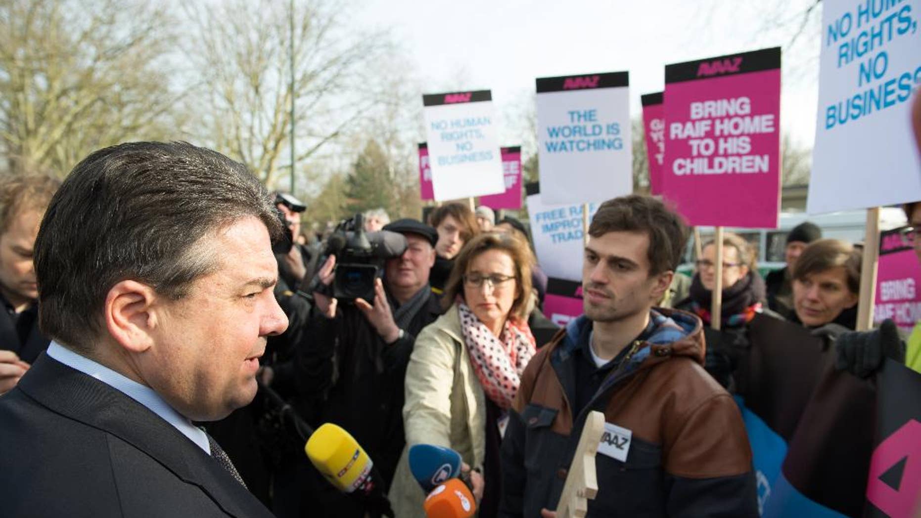In this Saturday March 7, 2015 picture activists of the global civic movement Avaaz hand over signatures of an online petition to Germany's Minister of Economic Affairs and Energy, Sigmar Gabriel, left, during a demonstration in front of the military airport of Tegel Berlin. Gabriel, stopped on his way to board a plane to Saudi Arabia. The petition wants to help free the Saudi Blogger Raif Badawi, Shortly before meeting with the Saudi king on Sunday, German vice chancellor Sigmar Gabriel criticized a court-ordered punishment against the Saudi blogger who was sentenced to 10 years in prison and 1,000 lashes for insulting Islam on a liberal blog. (AP Photo/dpa, Bernd von Jutrczenka)