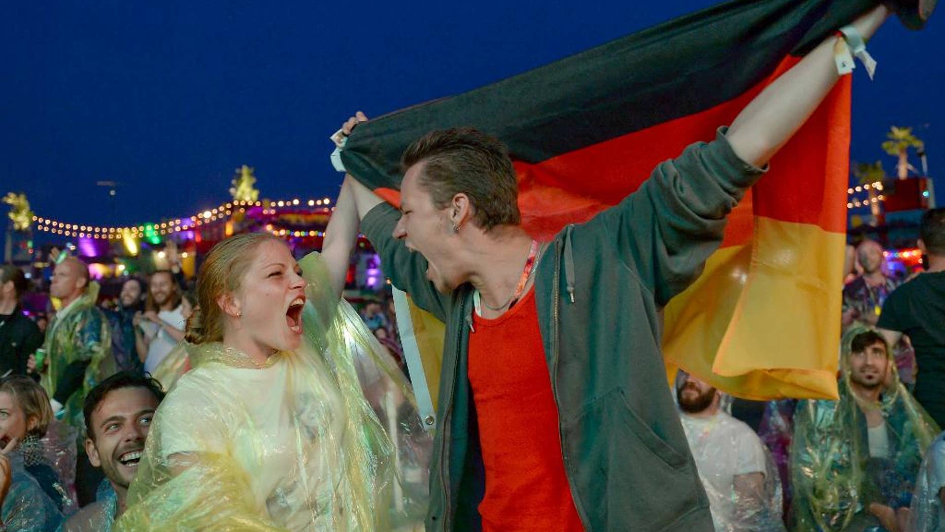 Soccer fans Daniel and Maryan celebrate as they watch the semifinal of the 2014 soccer World Cup between Brazil and Germany on the sidelines of the 'Bread & Butter' fair in Berlin, Tuesday evening, July 8, 2014. (AP Photo/dpa, Britta Pedersen)