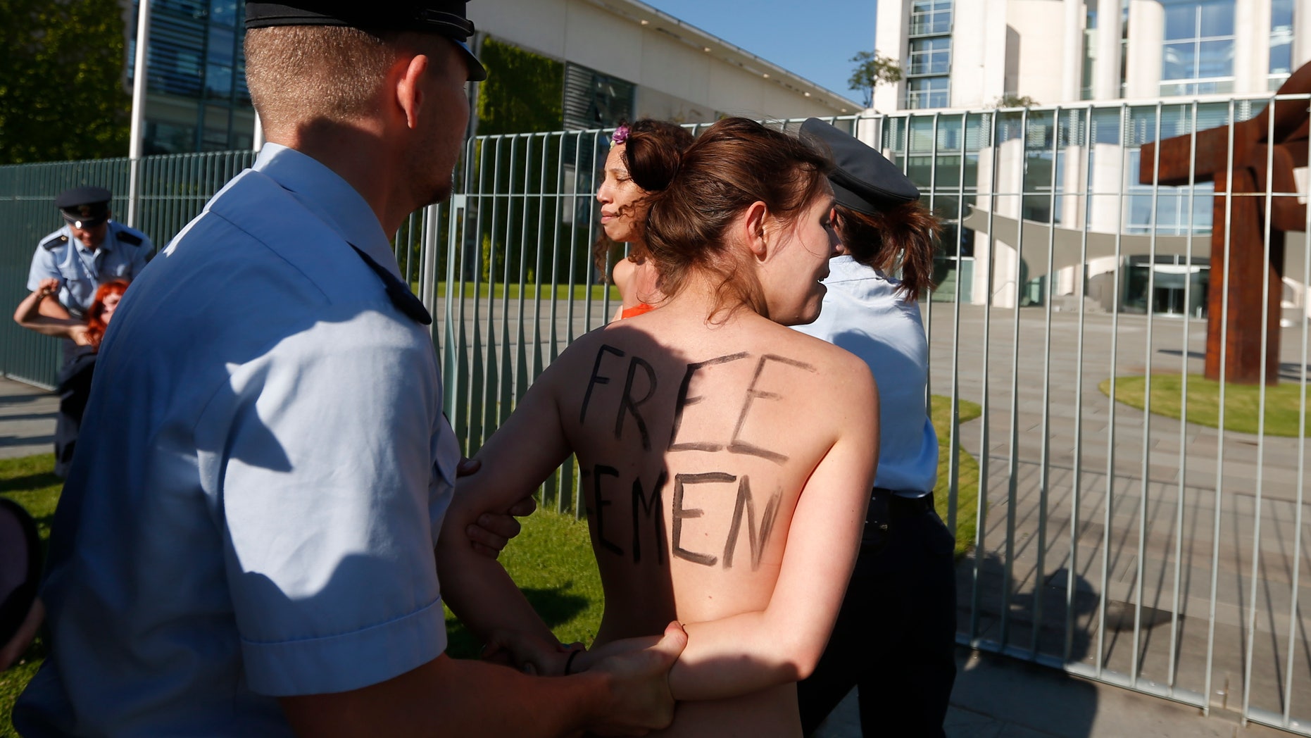 June 7, 2013: Activists from the women's movement Femen are being stopped by police officers during a protest in front of the German chancellery ahead of the visit of Tunisian Prime Minister Ali Laarayedh in Berlin. Three topless Femen protesters pleading for Angela Merkel to push for the release of four fellow activists jailed in Tunisia.