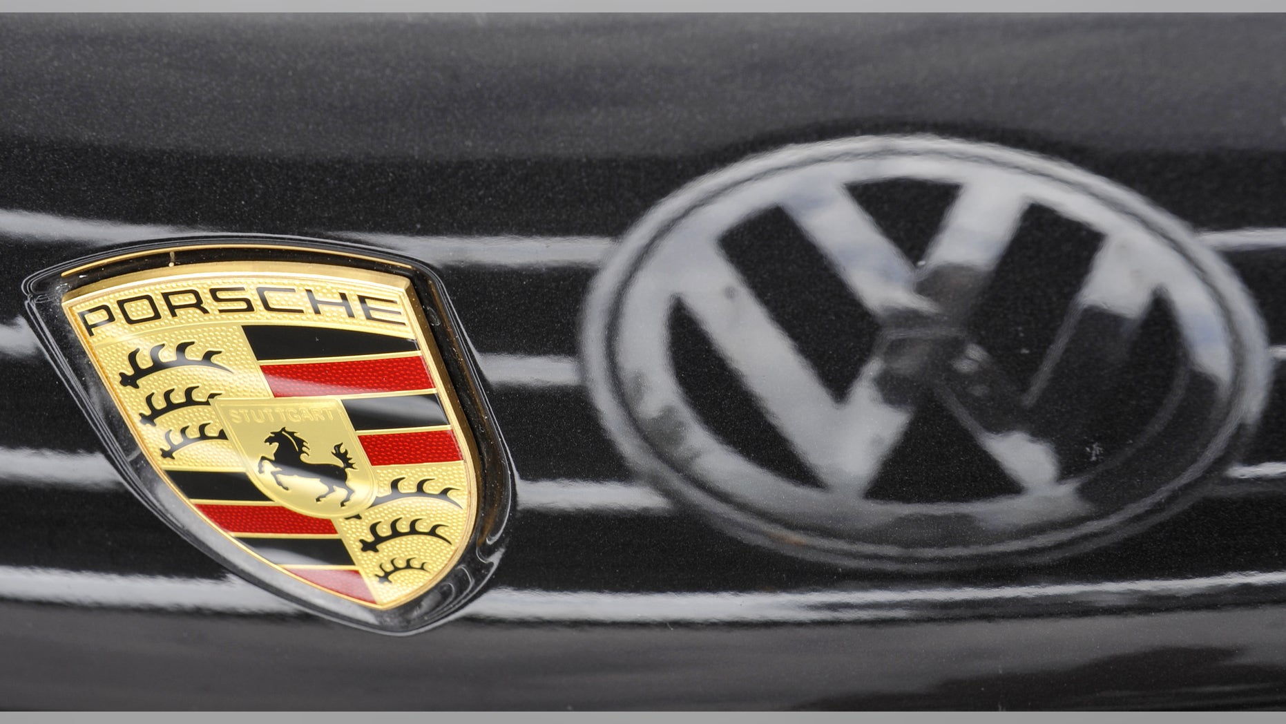 FILE - In this June 29, 2009 file picture a a logo of a car of German car maker Volkswagen VW is reflected in the varnish of a Porsche sports car in Dresden. Shares in Volkswagen AG soared higher on Thursday July 5, 2012 after Europe's biggest automaker announced a deal to complete the takeover of sports car manufacturer Porsche by the end of the month, which the company said will result in savings of some 700 million euro (US $ 880 million) per year. Volkswagen is to acquire the 50.1 percent in Porsche's capital that it doesn't already hold from holding company Porsche SE for 4.46 billion euro plus one Volkswagen share. The arrangement allows it to book the acquisition as an internal reorganization, which is advantageous in tax terms. (AP Photo/ Matthias Rietschel,File)