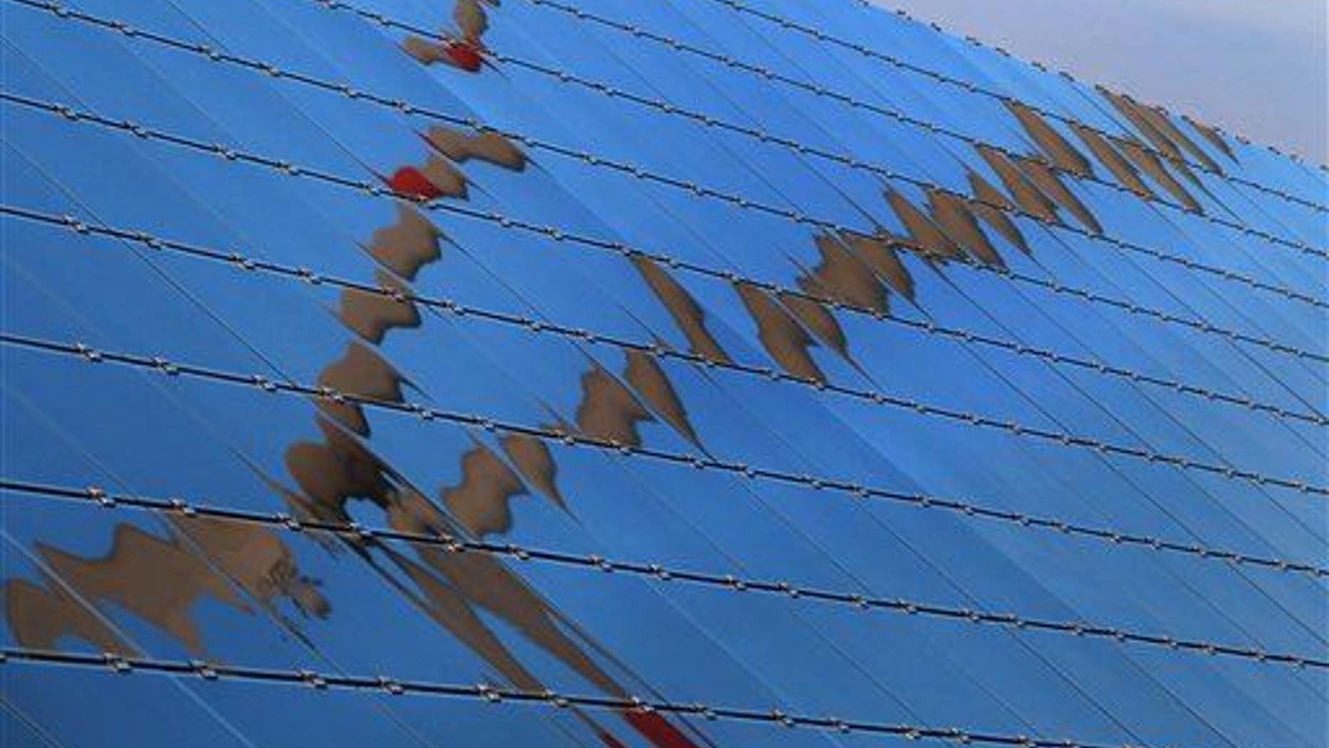 A wind turbine is reflected in the panels of a solar field in Biebelried, Germany, in 2013.