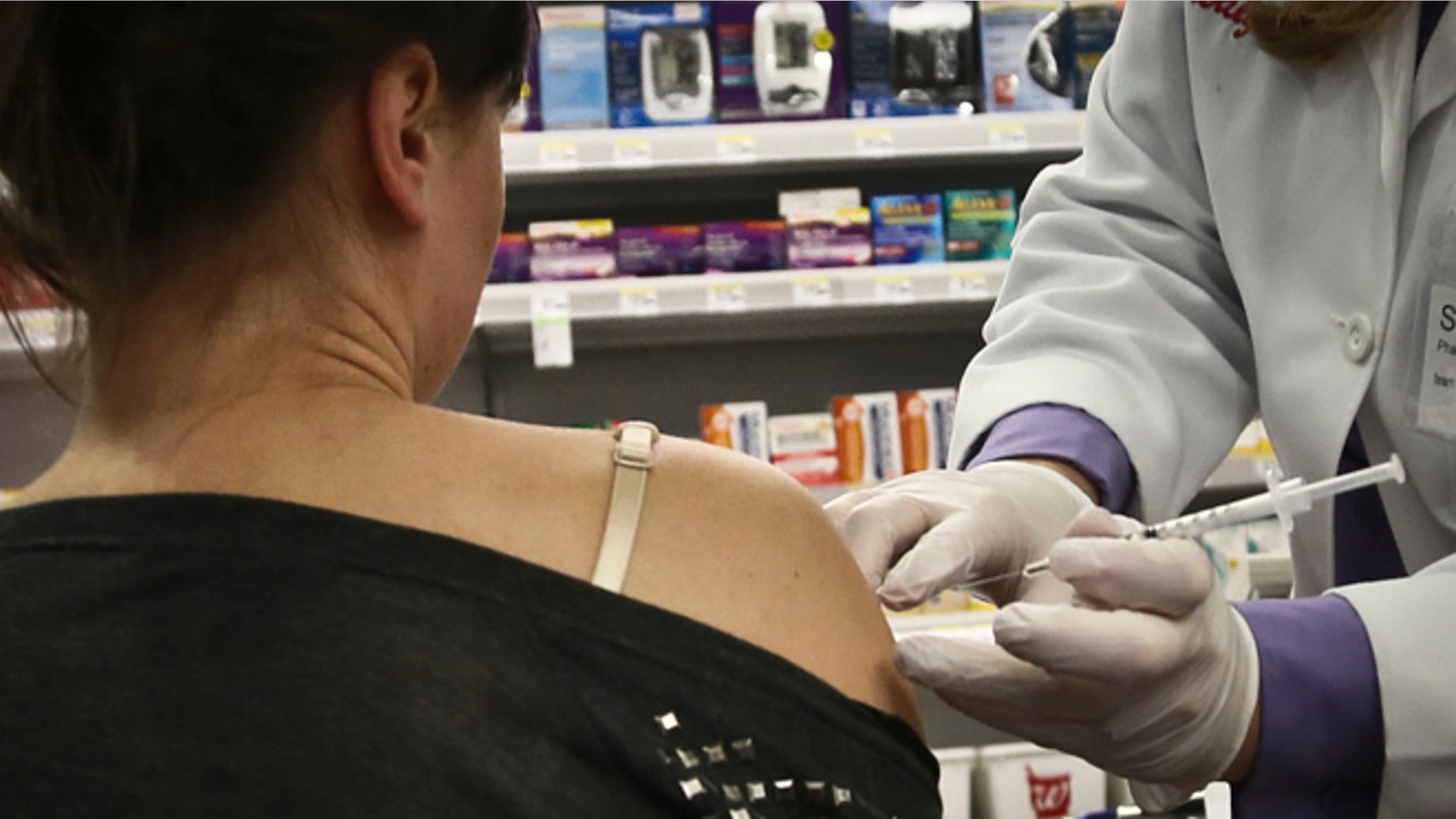 A pharmacy manager for Walgreens administers a flu vaccine on site.