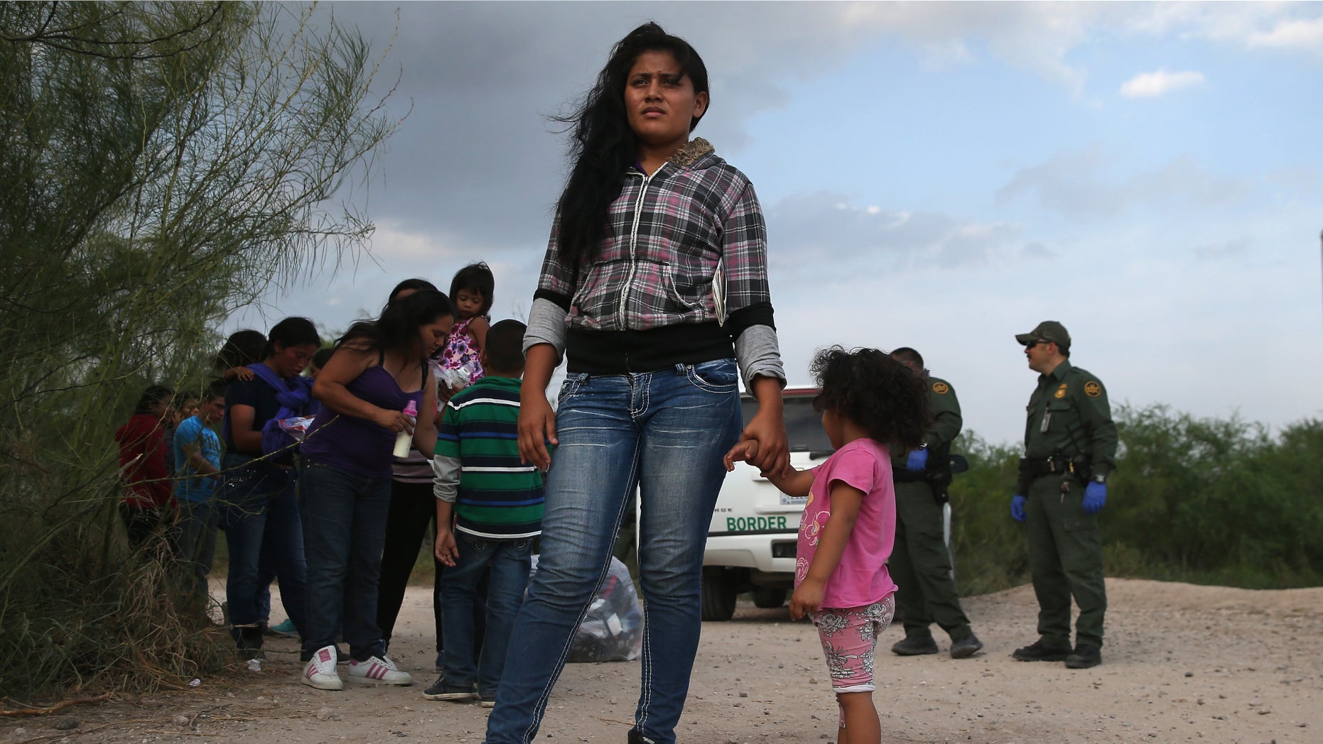 MISSION, TX - JULY 24: Honduran immigrants Maria Celeste Castro and her daughter Melida Patricio, 2, wait as a Border Patrol vehicle arrives to transport their group to a processing center after they crossed the Rio Grande into Texas on July 24, 2014 in Mission, Texas. Tens of thousands of immigrant families and unaccompanied minors from Central America have crossed illegally into the United States this year and presented themselves to federal agents, causing a humanitarian crisis on the U.S.-Mexico border. Texas' Rio Grande Valley has become the epicenter of the latest immigrant crisis, as more of them enter from Mexico into that sector than any other stretch of the America's 1,933 mile border with Mexico. (Photo by John Moore/Getty Images)