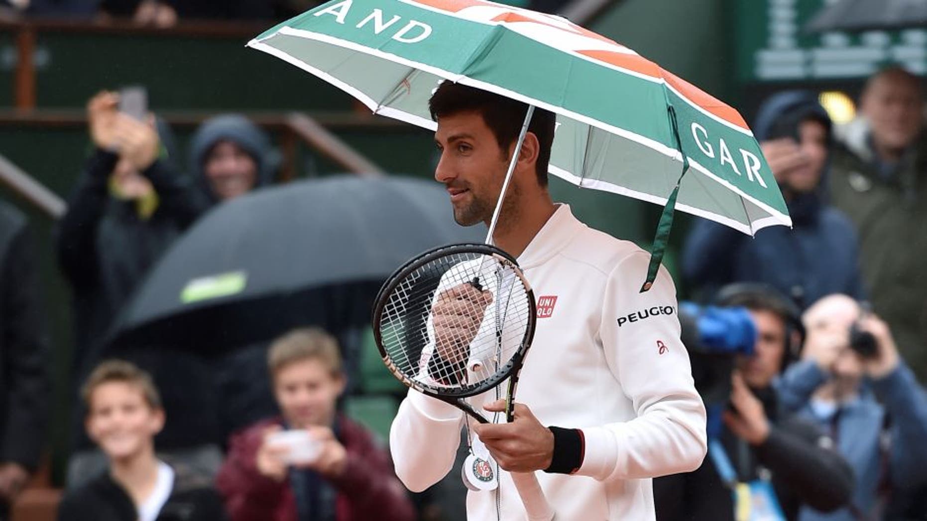 Serbia's Novak Djokovic holds up an umbrella before resuming his men's fourth round match against Spain's Roberto Bautista-Agut at the Roland Garros 2016 French Tennis Open in Paris on May 31, 2016. / AFP / Eric FEFERBERG (Photo credit should read ERIC FEFERBERG/AFP/Getty Images)