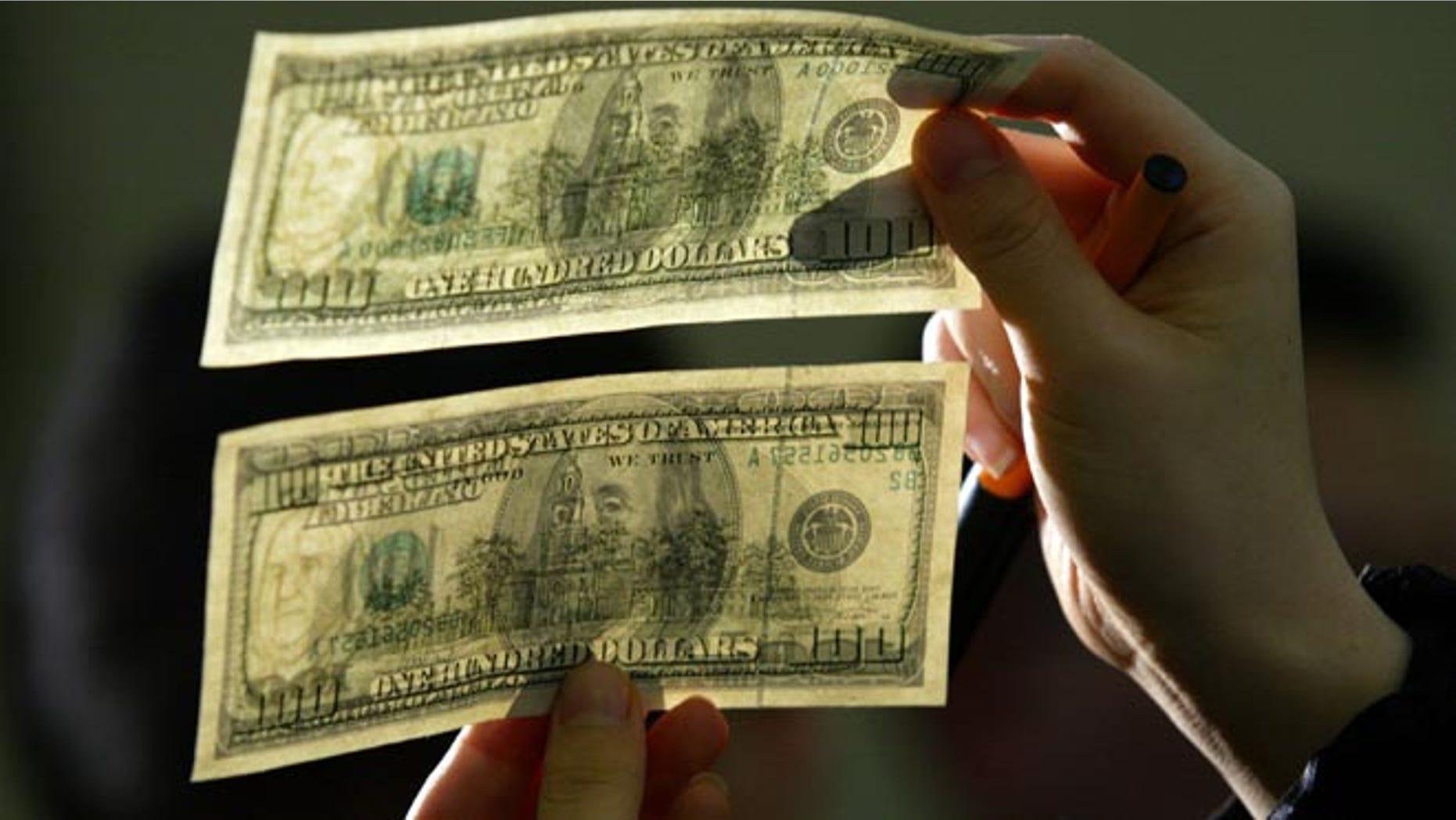 SEOUL, SOUTH KOREA - FEBRUARY 23: South Korean lawmaker Kim Moon-Soo shows a genuine U.S. $100 note above a counterfeit one during a news conference at the National Assembly February 23, 2006 in Seoul, South Korea. Kim, who obtained the counterfeit through human rights activists in the Chinese city of Dandong bordering North Korea, is urging the South Korean government to deal with North Korea's alleged counterfeiting more sternly. (Photo by Chung Sung-Jun/Getty Images)