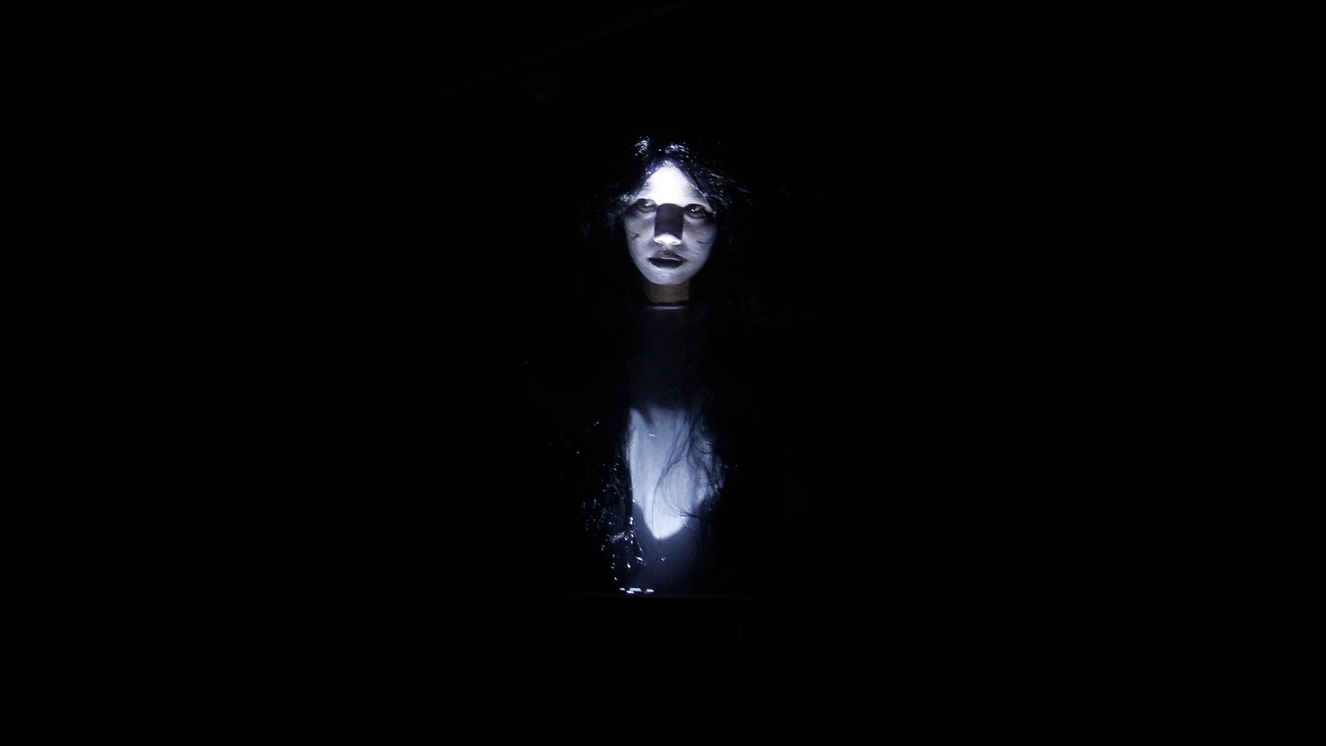 An actress dressed as a ghost scares people entering a "haunted school" during a Halloween celebration at a mall in Manila Oct. 31, 2012.