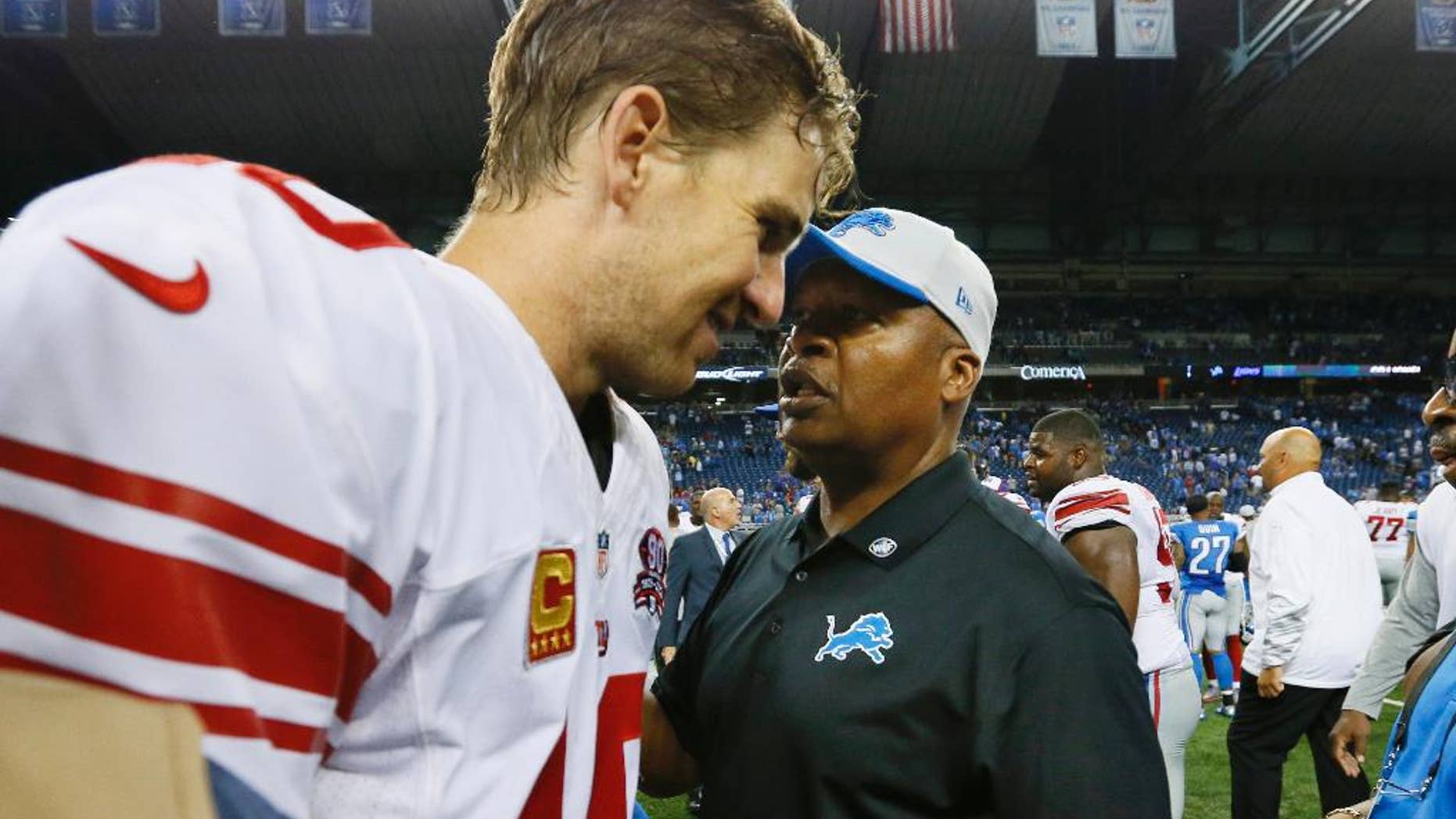 New York Giants quarterback Eli Manning, left, talks with Detroit Lions head coach Jim Caldwell after their NFL football game in Detroit, Monday, Sept. 8, 2014. (AP Photo/Paul Sancya)