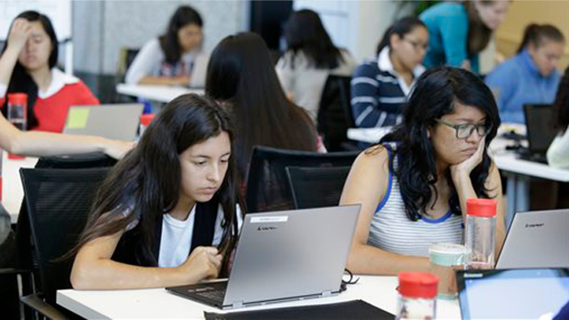 In this photo taken Wednesday, June 18, 2014, Bryanna Gilges, 15, left, and Yvonne Gonzalez, 17, right, work at completing an exercise during a Girls Who Code class at Adobe Systems in San Jose, Calif. Google is partnering with Girls Who Code, a national non-profit organization that aims to inspire, educate and equip young women for futures in the computing-related fields. (AP Photo/Eric Risberg)