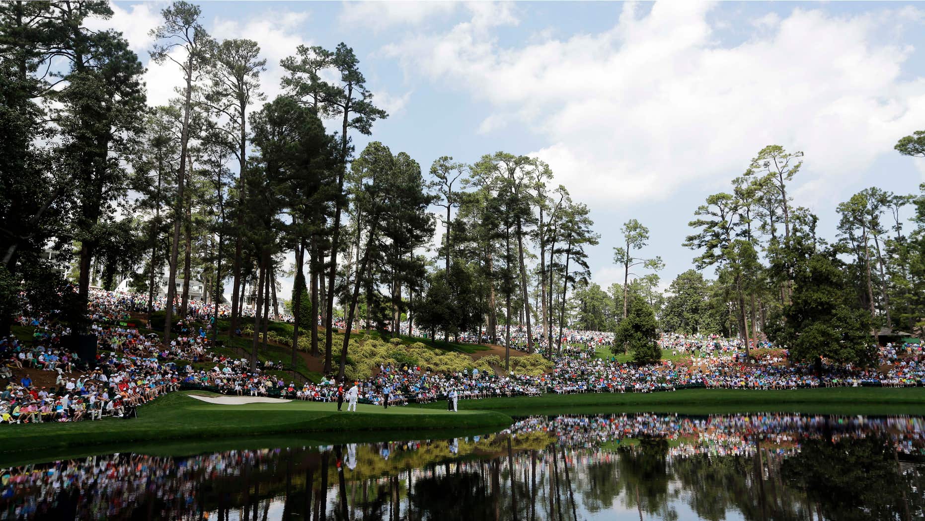 April 8, 2015: Spectators sit around the ninth hole during the Par 3 contest at the Masters golf tournament.