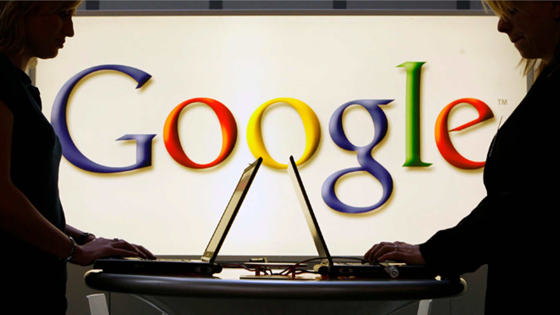 FILE - In this April 17, 2007 file photo, exhibitors work on laptop computers in front of an illuminated Google logo at the industrial fair Hannover Messe in Hanover, Germany. Google said Thursday, Dec. 11, 2014 it will shut down its Google News service in Spain to prevent publishers' content from appearing on it ahead of a new law requiring the Internet search company to pay Spanish news organizations for linked content or snippets of news. (AP Photo/Jens Meyer, File)