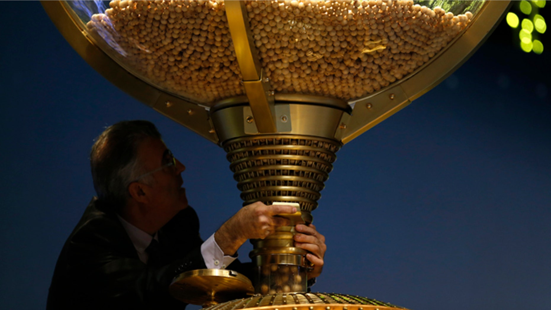 A worker opens a trap-door in a giant drum to let the balls bearing ticket numbers fall into a lower compartment before the start of Spain's Christmas lottery, in Madrid, Tuesday, Dec. 22, 2015. Celebrations were guaranteed Tuesday in the southern beach town of Roquetas de Mar, southern east Spain, where tickets bearing the top prize number of 79140 in Spain's Christmas lottery, known as "El Gordo" (The Fat One) were sold. The number appeared on 1,600 tickets, known as decimos (tenths) with each holder winning 400,000 euros ($434,800). The tickets are usually sold in many different lottery sales points making it virtually impossible to win the entire 640 million euros assigned to the top prize number. (AP Photo/Francisco Seco)