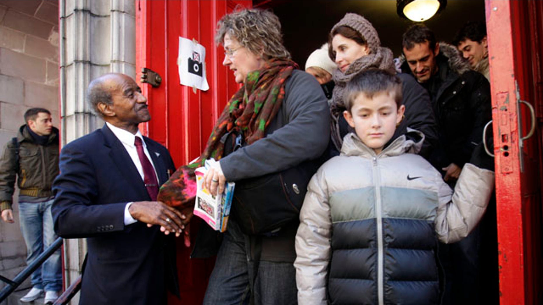 Congregant Clinton Johnson, second from left, shakes hands with departing tourists after a service at the Mother AME Zion Church in New York, Sunday, Feb. 26, 2012.