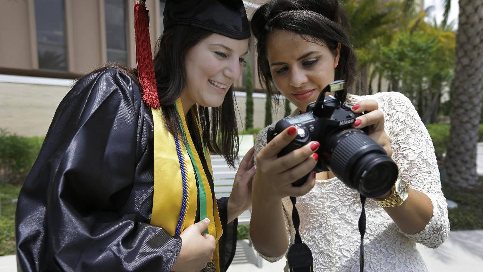April 29, 2014: University of South Florida graduating seniors Kyra Ciotti, 22, of Tampa, Fla., left, and Rita Sibaja, 24, of Winter Haven, Fla., look at photos that Rita took of Kyra in her cap and gown Tuesday, April 29, 2014, in Tampa, Fla. The university has banned all self portraits, also known as "selfies," during their 2014 graduation exercises. (AP/Chris O'Meara)