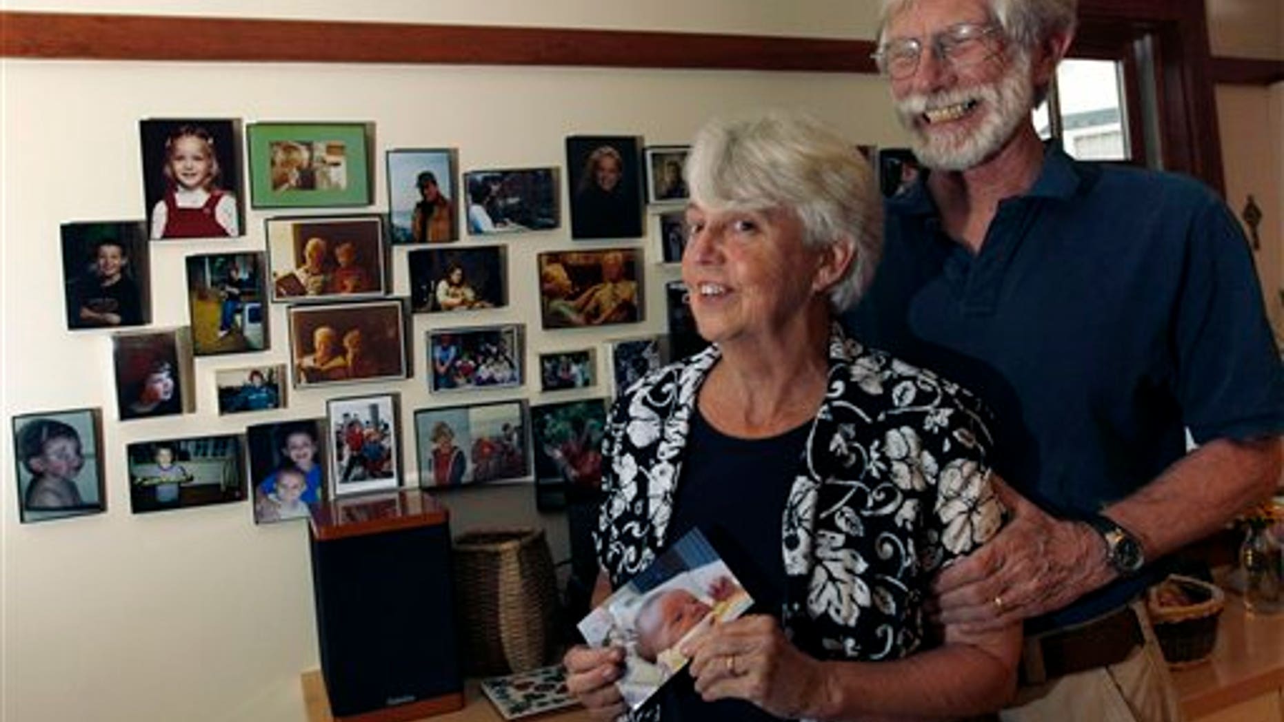 August 24: Eileen and Doug Flockhart laugh as she holds a picture of their seventh grandchild near a wall full of family photos in their home in Exeter, N.H.