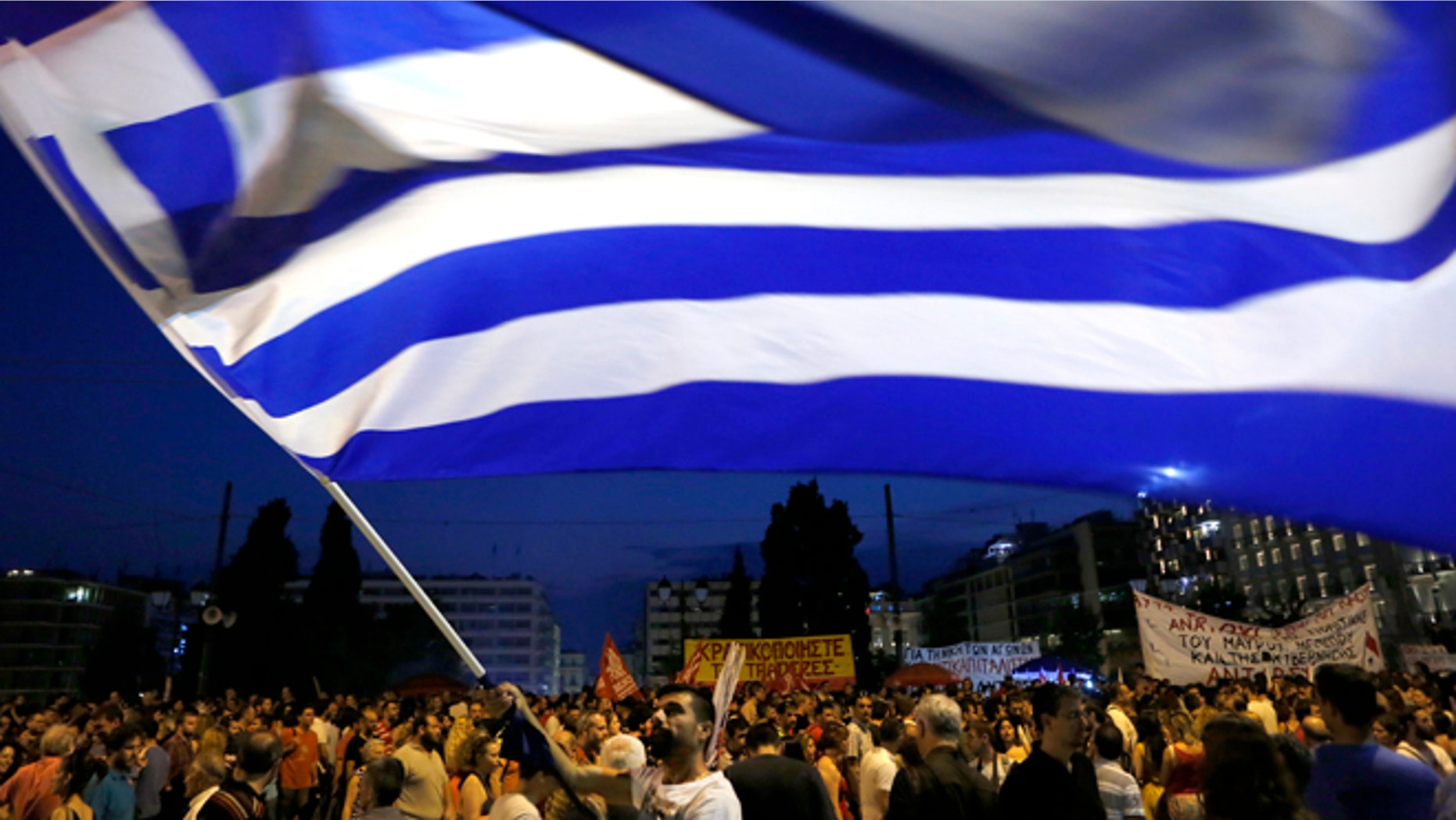A demonstrator waves a Greek flag during an anti-austerity rally in central Athens, Friday, July 10, 2015. Greek Prime Minister Alexis Tsipras sought his left-wing party's backing on Friday for a new budget austerity package that is harsher than what he urged Greeks to reject in a vote just last week, but would provide the country will longer-term financial support. (AP Photo/Petros Karadjias)