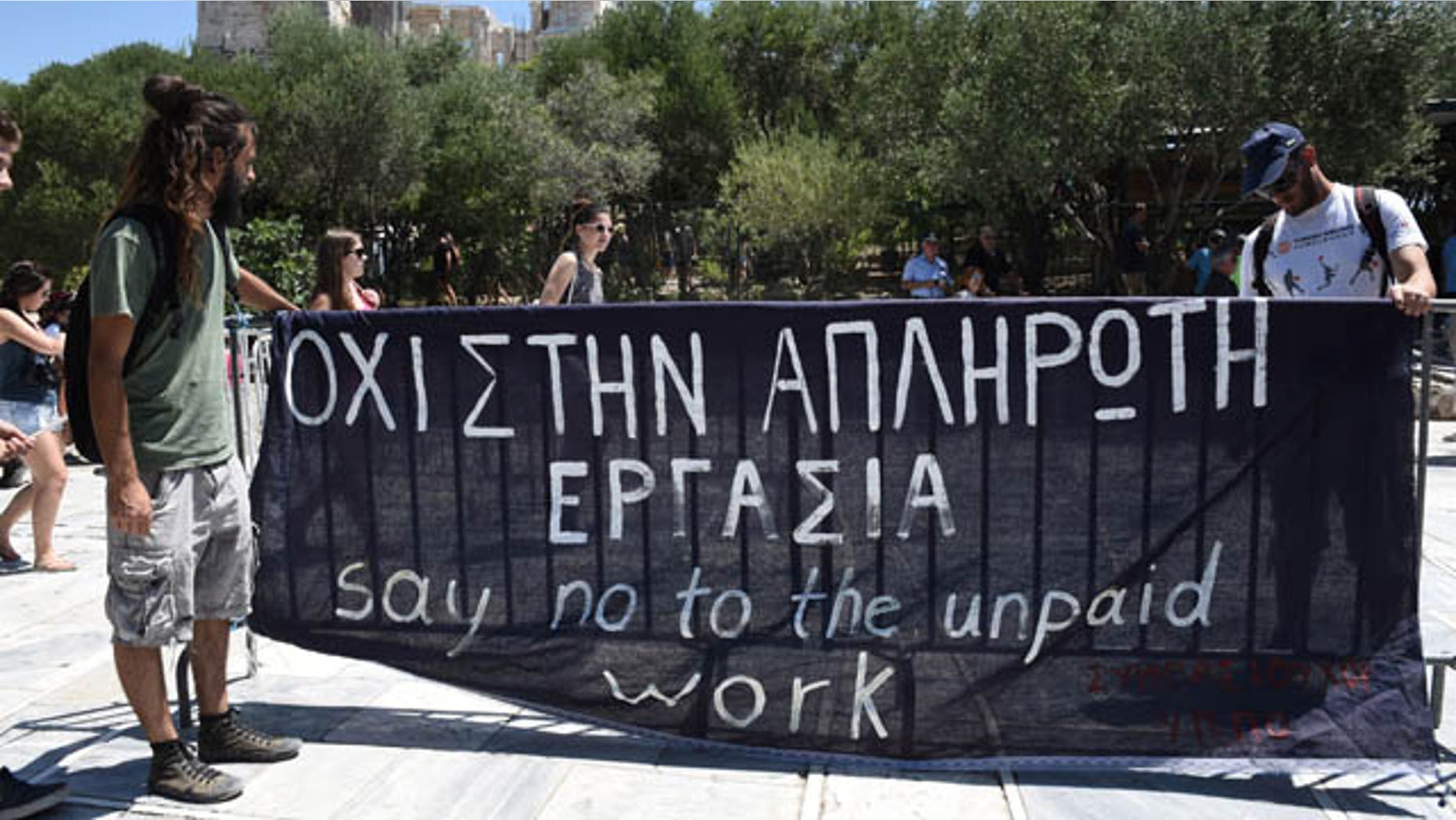 Short-term contract employees of the Culture Ministry, unpaid for over six months, protest outside the entrance of the ancient Acropolis hill in Athens, Thursday, July 23, 2015. Greece's radical left-led government survived another revolt by rebels in the early hours of Thursday, passing reforms that should pave the way for the imminent start of bailout discussions with European creditors. Sign says in Greek and English "Say no to the unpaid work." (AP Photo/Giannis Papanikos)