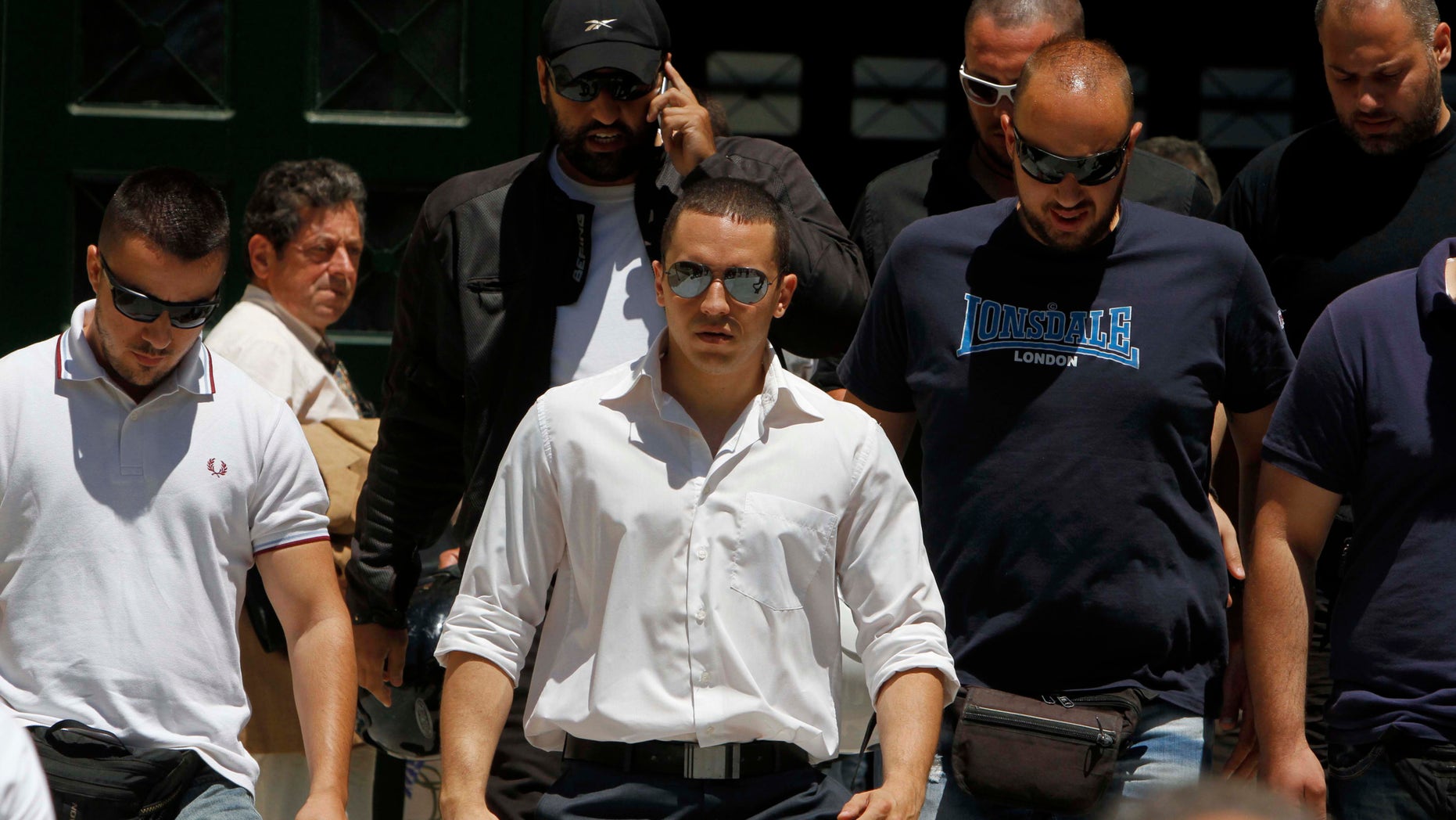 June 11, 2012: The spokesman of Greece's extreme-right Golden Dawn party Ilias Kasidiaris, center, is escorted by party members as they exit the prosecutor's office in Athens.