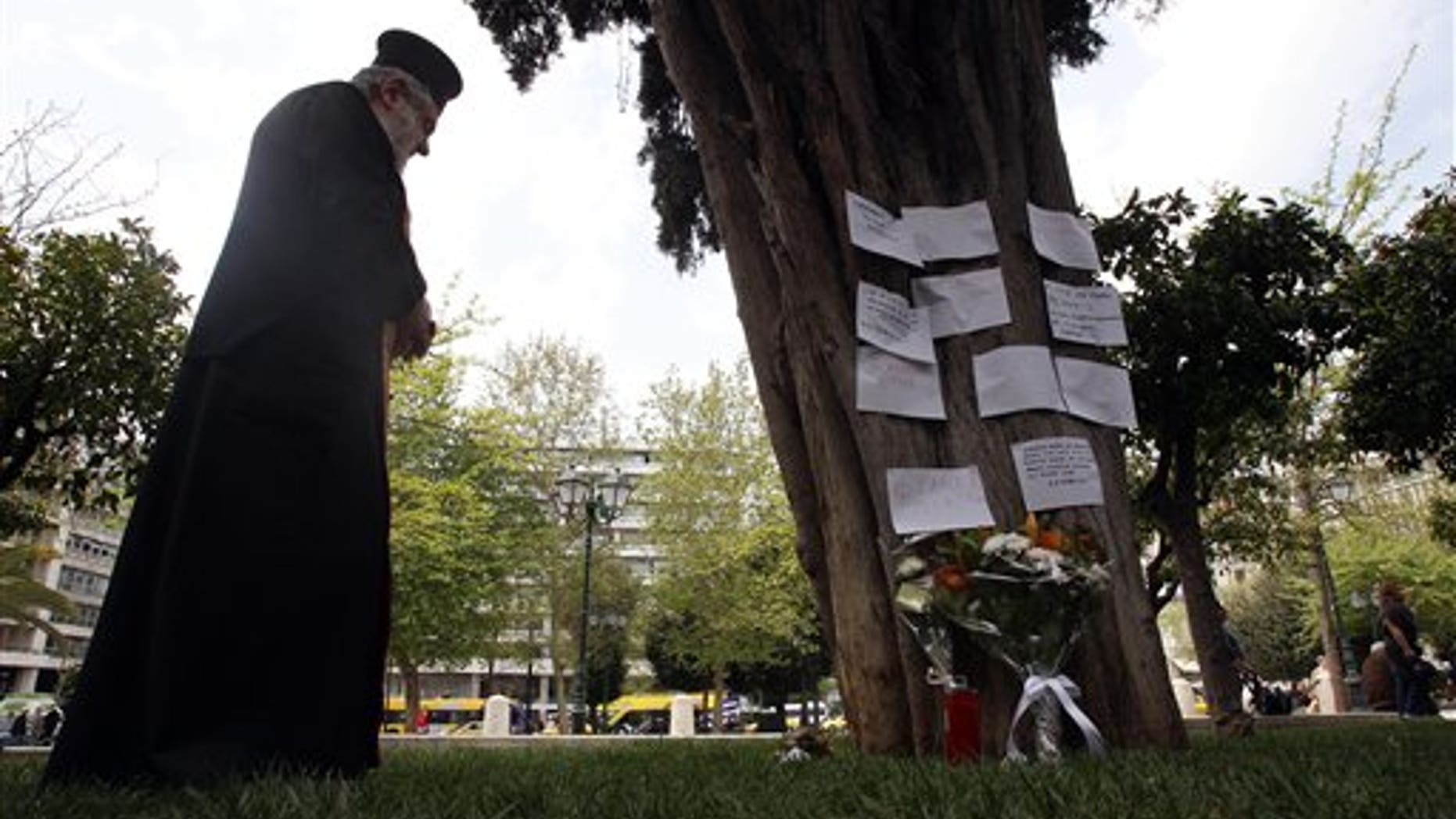 April 4, 2012: A Greek Orthodox priest holds a memorial service, at the site where an elderly man fatally shot himself at Athens' main Syntagma square.