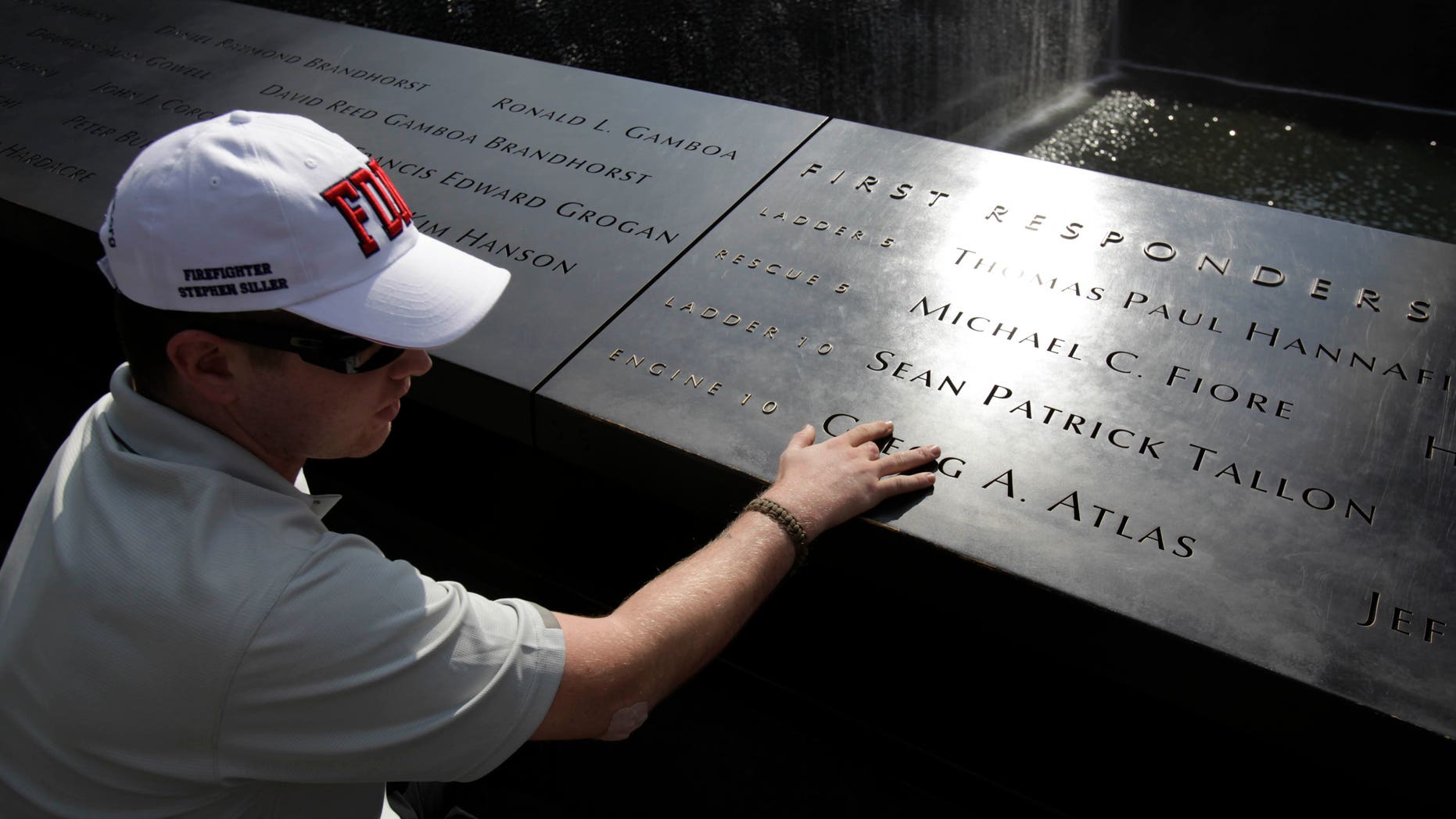 July 4- US Army PFC Kyle Hockenberry of Marietta, Ohio, touches the name of a first responder etched in the 9/11 Memorial at ground zero in New York.