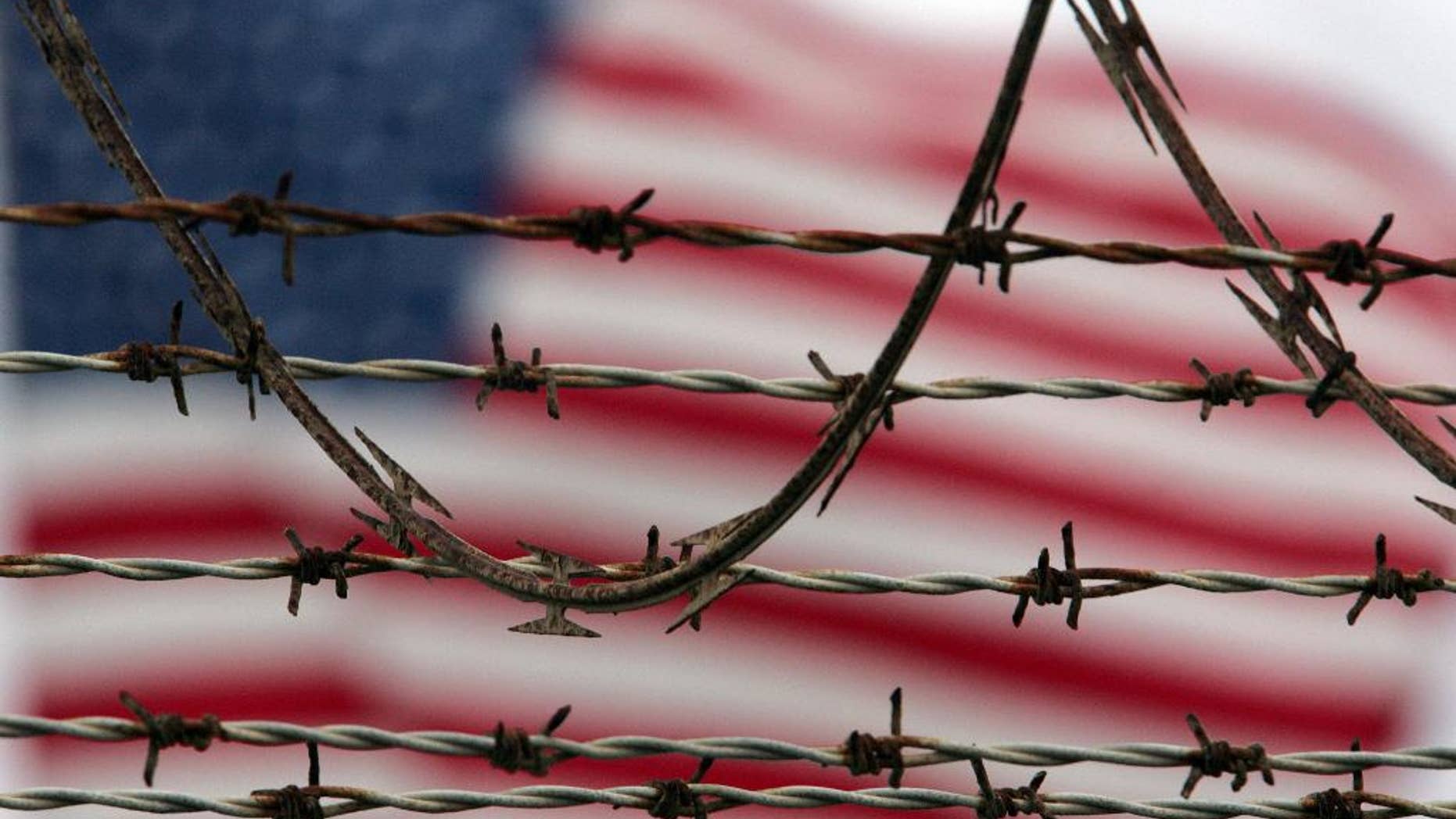 ** FILE ** In this Oct. 10, 2007 file photo, reviewed by the U.S. Military, an American flag flies behind the barbed and razor-wire at the Camp Delta detention facility, at Guantanamo Bay U.S. Naval Base, Cuba. The Pentagon said Saturday that four Afghans from the Guantanamo Bay detention center have been returned to their home country in what U.S. officials are citing as a sign of their confidence in new Afghan President Ashraf Ghani. (AP Photo/Brennan Linsley)