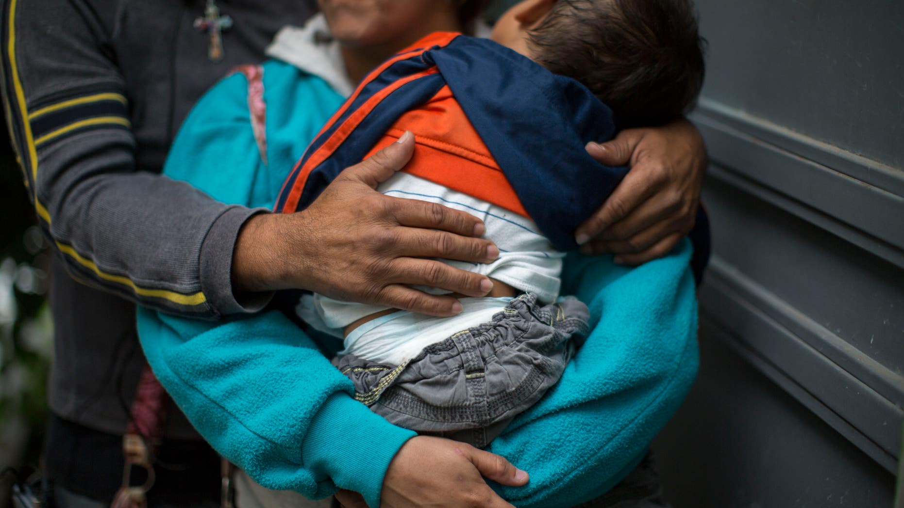 In this June 19, 2014 photo, a Honduran man hugs his wife as she carries their son at a immigrant shelter in Guatemala City.