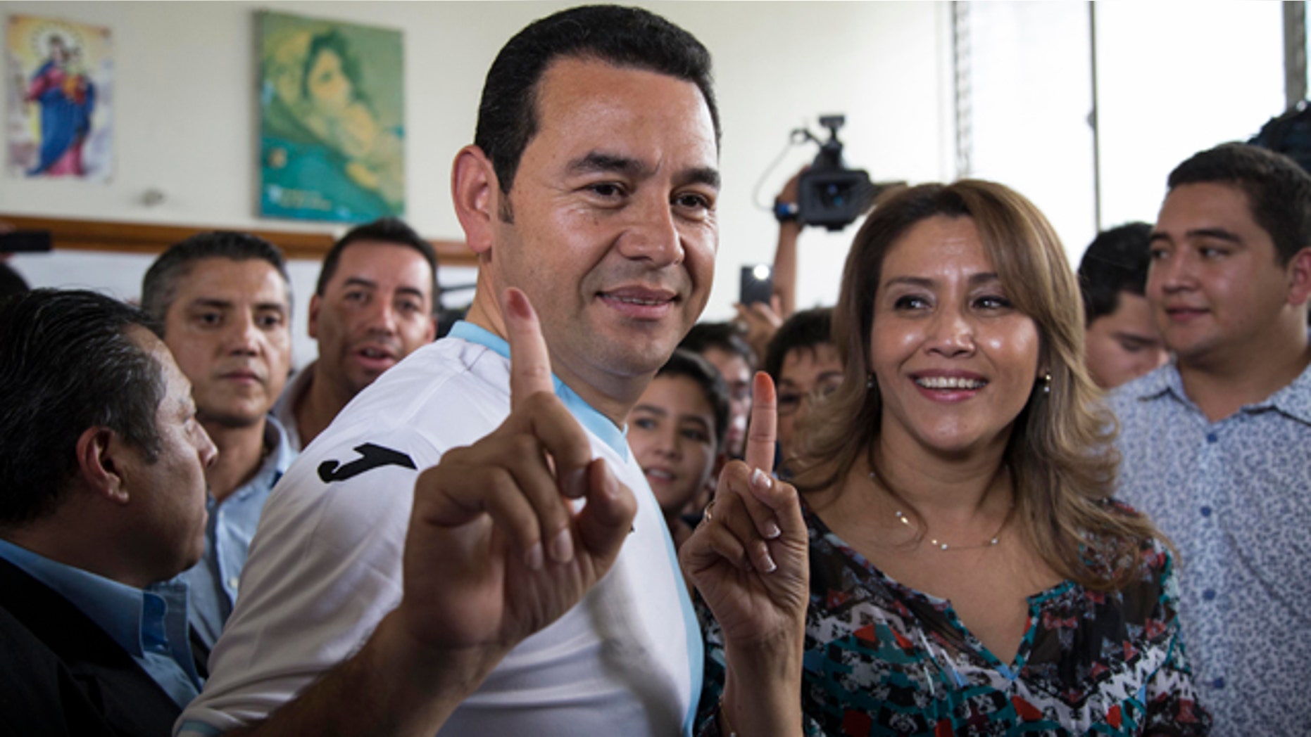 Oct. 25, 2015: Jimmy Morales, the National Front of Convergence party candidate, wearing the Guatemalan national soccer team jersey, accompanied by his wife Hilda Patricia Morales, show their inked fingers after casting their votes during the presidential runoff election at a polling station in Mixco, Guatemala. (AP Photo/Luis Soto)
