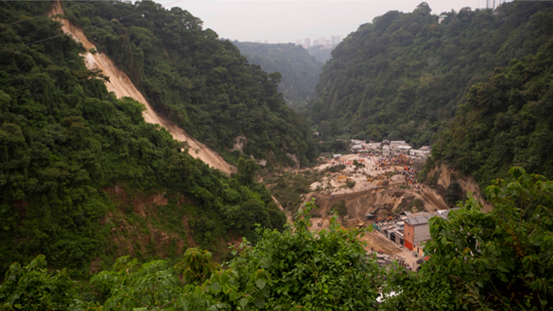 Rescue workers search for survivors after a landslide hit Cambray, a neighborhood in the suburb of Santa Catarina Pinula, about 10 miles east of Guatemala City, Friday, Oct. 2, 2015. The hill that towers over Cambray collapsed late Thursday after heavy rains, burying several houses with dirt, mud and rocks. (AP Photo/Moises Castillo)
