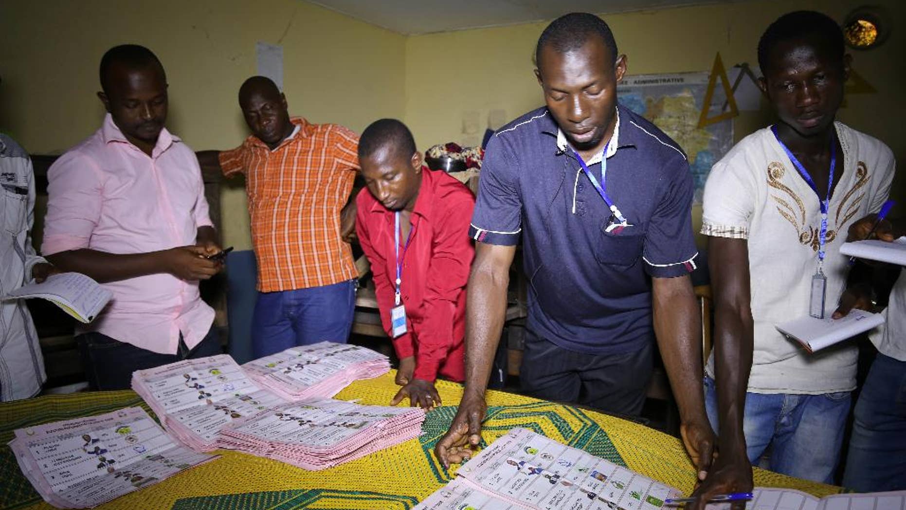 Electoral officials sort out ballot papers at the end of presidential elections in Conakry, Guinea, Sunday, Oct. 11, 2015. Guinea's president and main opposition candidate called for calm Sunday when they voted in the country's presidential election, after days of electoral clashes. (AP Photo/Youssouf Bah)