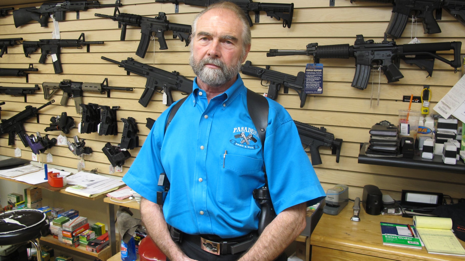 Sept. 26, 2013: Frank Loane, owner of Pasadena Pawn and Gun, stands in front of a wall of assault rifles at his store in Pasadena, Md.