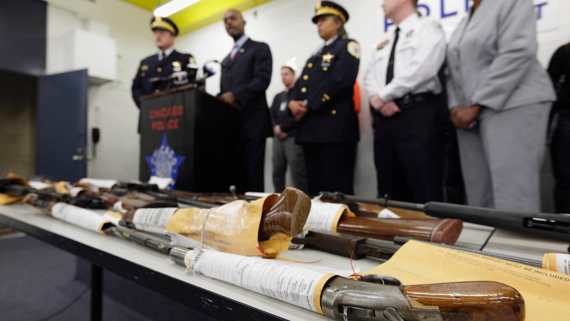 FILE - In this Jan. 28, 2013, file photo, Chicago Police First Deputy Superintendent Alfonsa Wysinger, second from left, speaks at a news conference in Chicago with a display of recently seized guns, part of the 574 that had been seized in the city since Jan. 1. The mounting homicide toll in President Barack Obamas hometown has giving ammunition to both sides in the nations debate about gun rights and safety. On Monday, Jan. 6, 2014, a federal judge in Chicago potentially opened a new market to gun dealers after ruling as unconstitutional Chicago ordinances that aim to reduce gun violence by banning their sale within the city's limits. (AP Photo/M. Spencer Green, File)