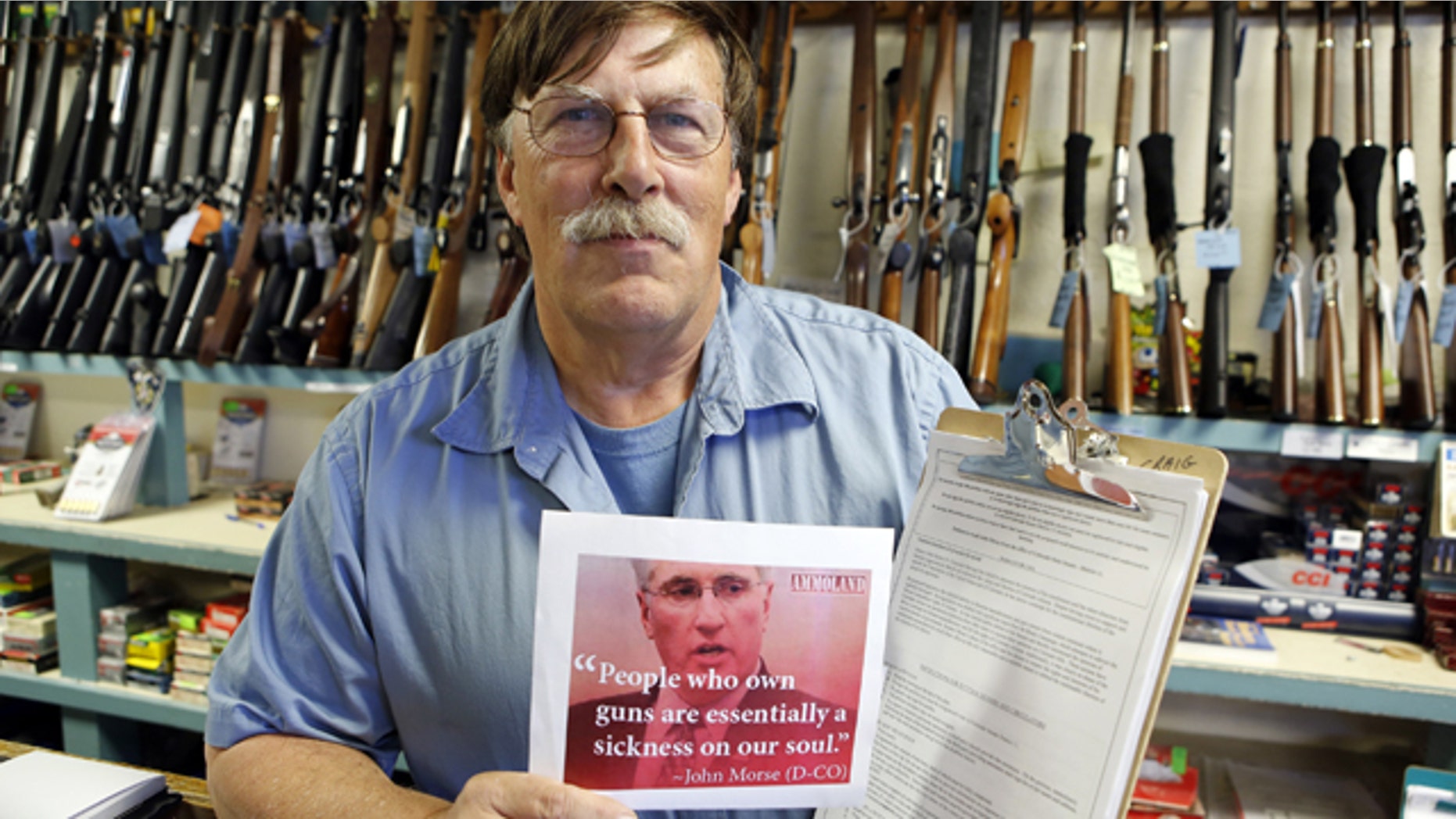 May 24, 2013: Paradise Firearms owner Paul Paradis holds a flyer depicting Colorado's State Senate President, Democrat John Morse, together with a petition to recall him, right, at his gun shop in Colorado Springs, Colo.
