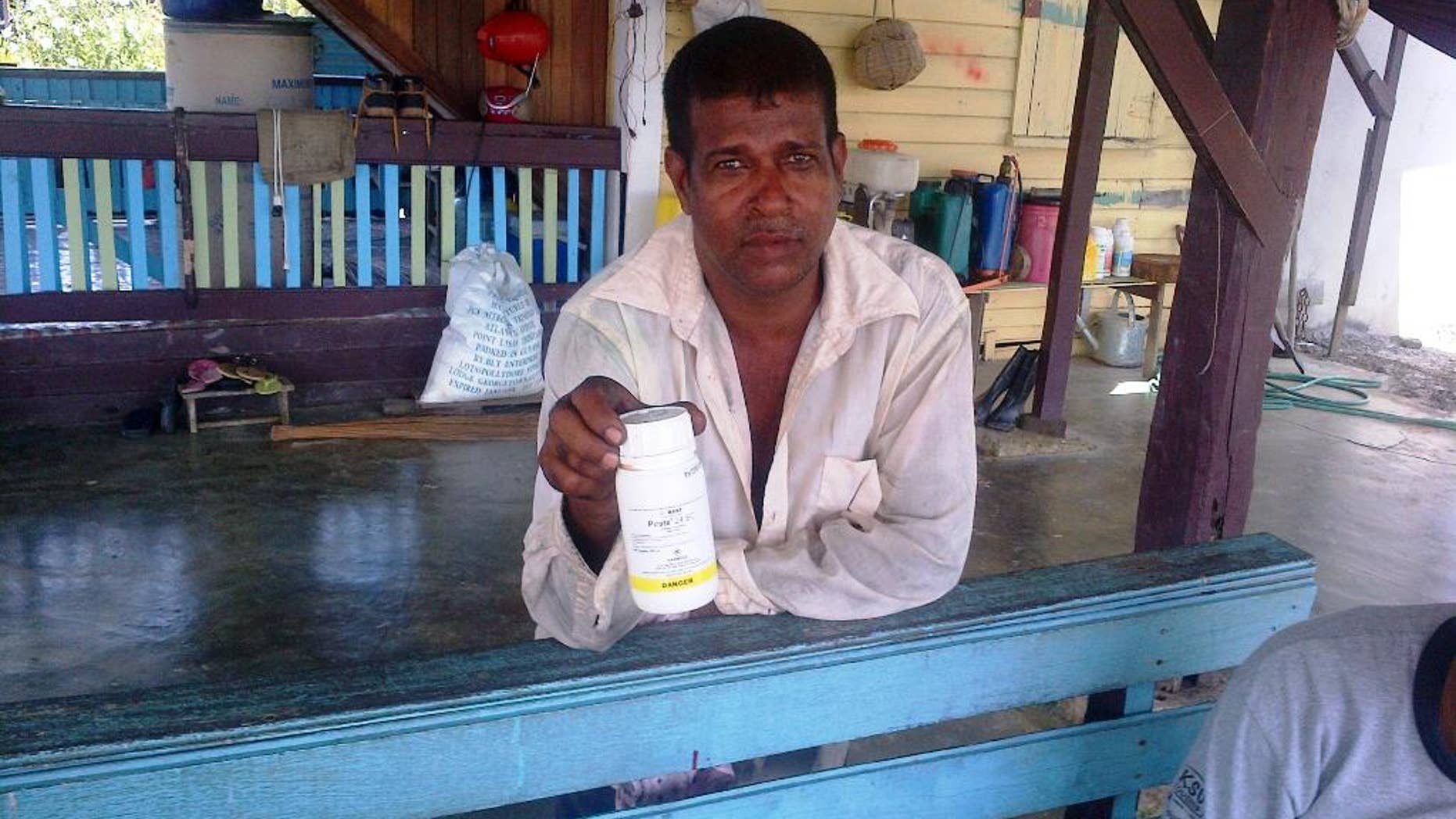 In this Monday, Oct. 6, 2014 photo, Vijai Ramlackhan holds a container of pesticide similar to the type his 17-year-old son used to commit suicide on their farm in the Berbice region of Guyana, a country that the World Health Organization says has the highest rate of suicide in the world. (AP Photo/Bert Wilkinson)