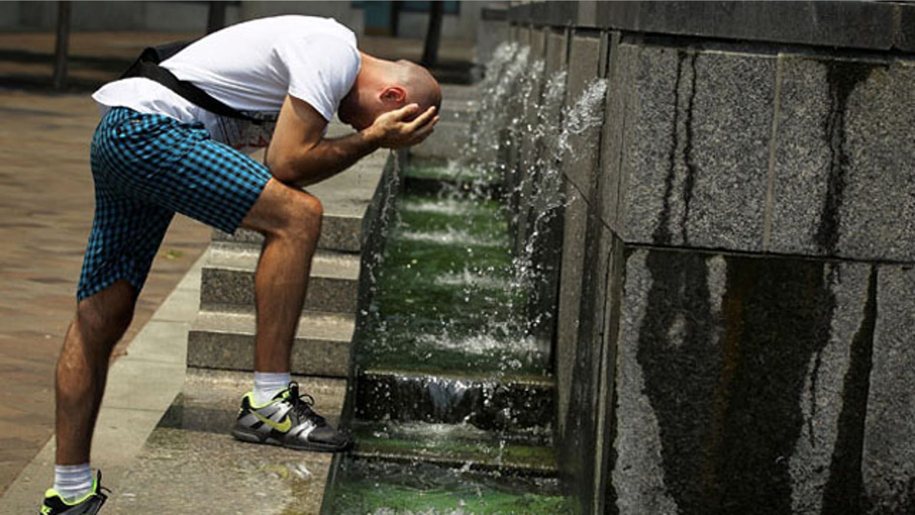WASHINGTON, DC - JUNE 22: Alexandar Zivkovic of Belgrade, Serbia, cools himself off at the fountain of the U.S. Navy Memorial June 22, 2012 in Washington, DC. Weather forecast predicted the area is heading towards a cooler weekend. (Photo by Alex Wong/Getty Images)