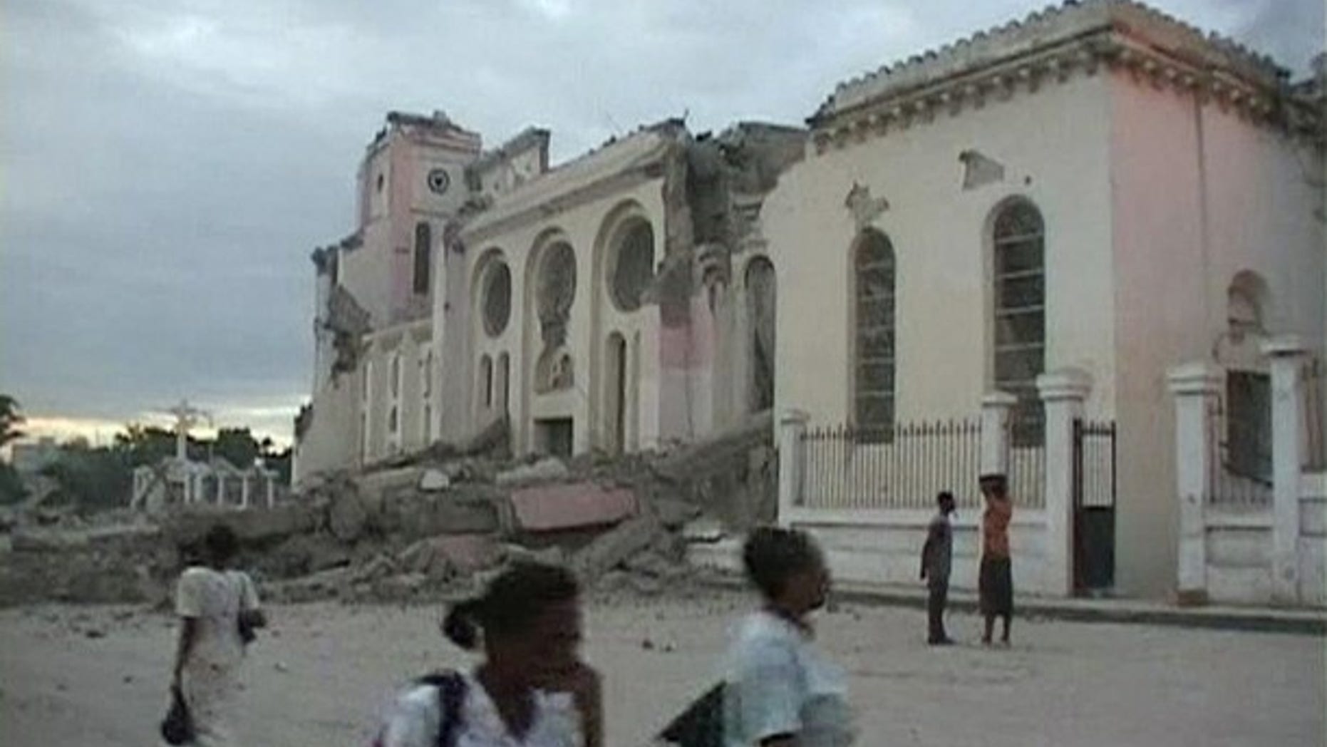 People walk near the ruins of a building, which was destroyed after a major earthquake struck near Port-au-Prince. The magnitude 7.0 quake toppled buildings and caused deaths and injuries.