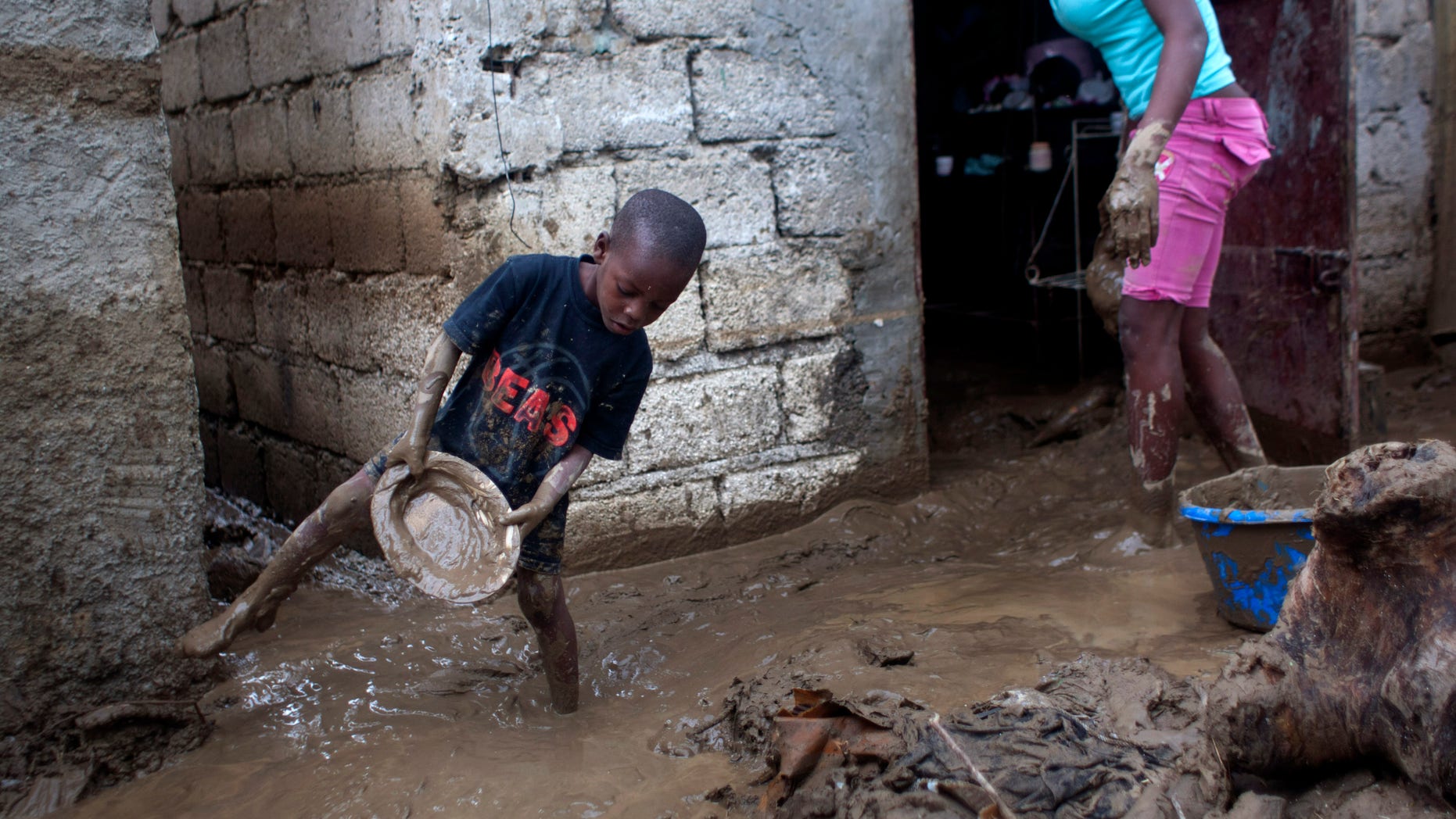 Sunday Aug. 26, 2012 - Winsky Pierre, 5, helps to drain mud from his flooded house after the passing of Tropical Storm Isaac in Port-au-Prince, Haiti.