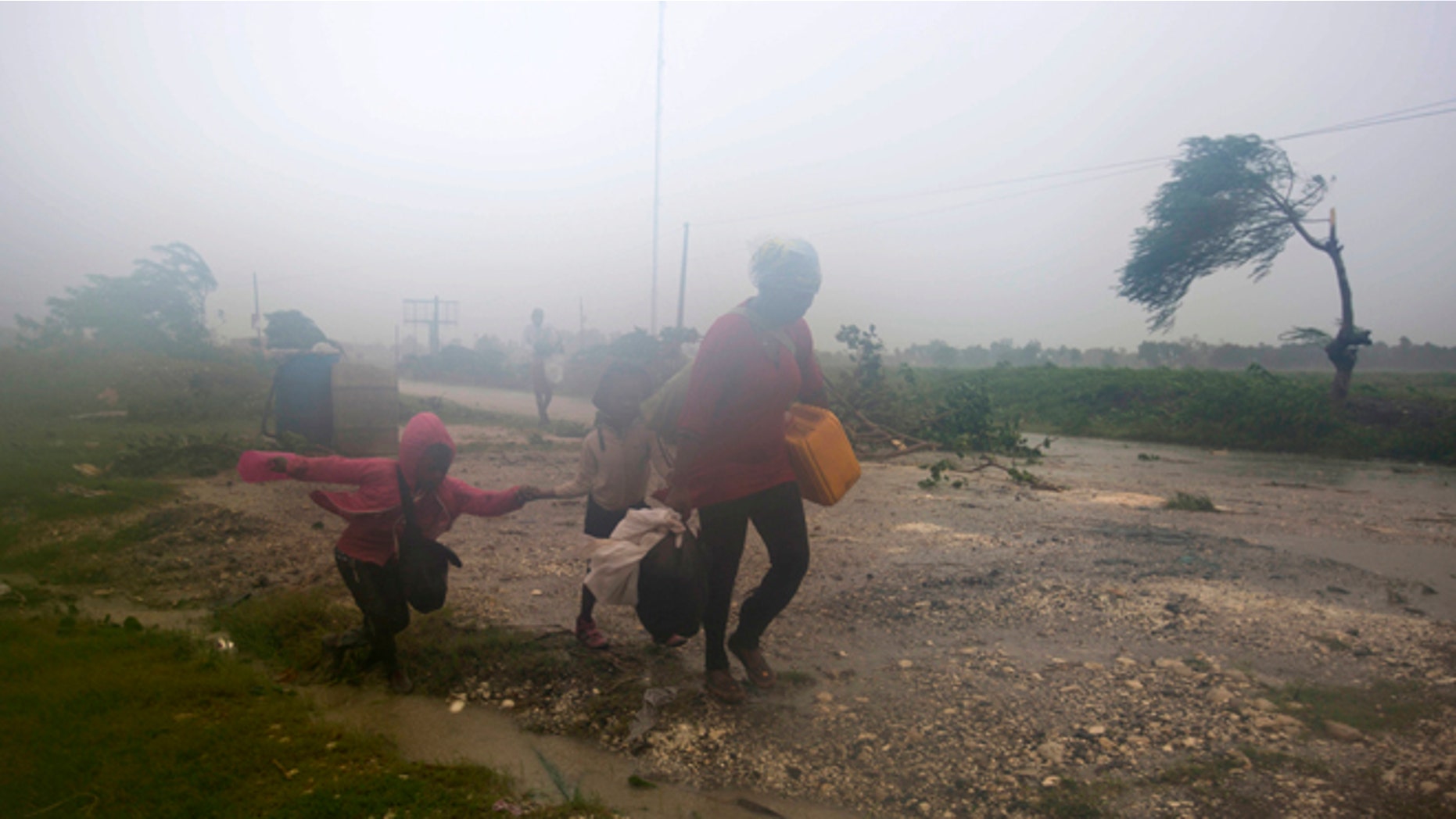 Residents head to a shelter in Leogane, Haiti, Tuesday, Oct. 4, 2016. Matthew slammed into Haiti's southwestern tip with howling, 145 mph winds Tuesday, tearing off roofs in the poor and largely rural area, uprooting trees and leaving rivers bloated and choked with debris. (AP Photo/Dieu Nalio Chery)