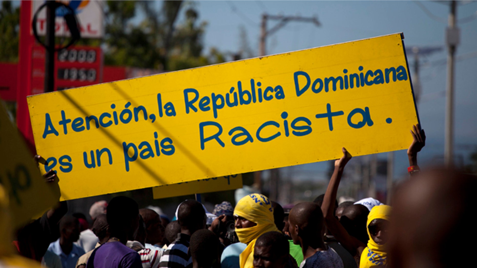 Protesters hold a banner that reads in Spanish; "Attention, the Dominican Republic is a racist country," in Port-au-Prince, Haiti, Friday, Dec. 6, 2013. Hundreds of people gathered near the Dominica Embassy decrying a recent court decision in the Dominican Republic that could strip the citizenship of generations of people of Haitian descent living in the neighboring country. (AP Photo/Dieu Nalio Chery)