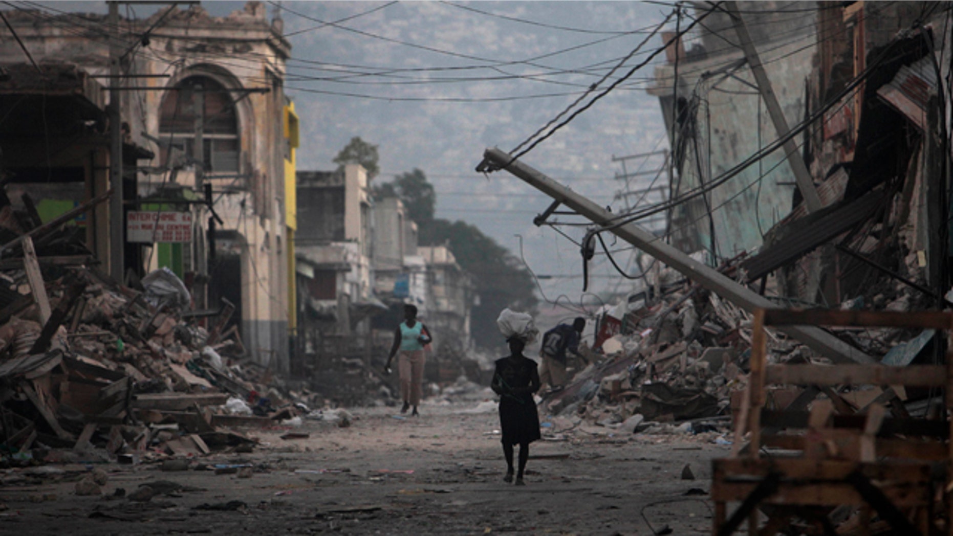 Jan. 20, 2010: A woman walks down a devastated street in Port-au-Prince, Haiti, a week after powerful 7.0-magnitude earthquake struck. Far fewer people died or were left homeless by last year's devastating earthquake than claimed by Haitian leaders, a report commissioned by the U.S. government has concluded.