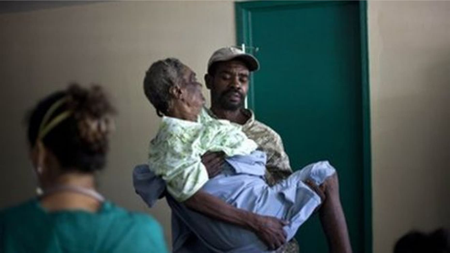 In this photo from Nov. 8, 2010, a woman suffering from cholera symptoms is carried by a volunteer at the hospital in Archaie, Haiti. (AP Photo)