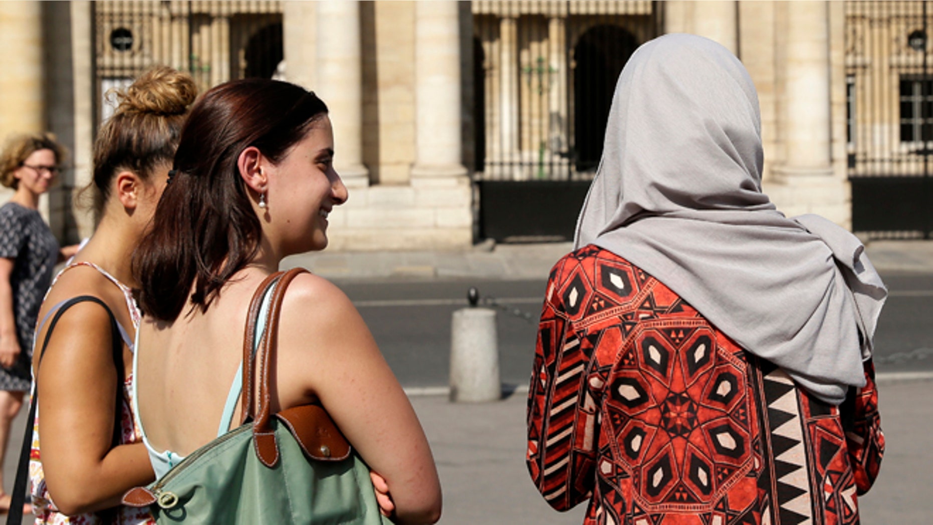 A woman wearing a Muslim headscarf, right, and who refused to be identified, stands outside the Conseil d'Etat, France's top administrative court, in Paris, Friday, Aug. 26, 2016. The court has overturned a town burkini ban amid shock and anger worldwide after some Muslim women were ordered to remove body-concealing garments on French Riviera beaches. (AP Photo/Thomas Padilla)