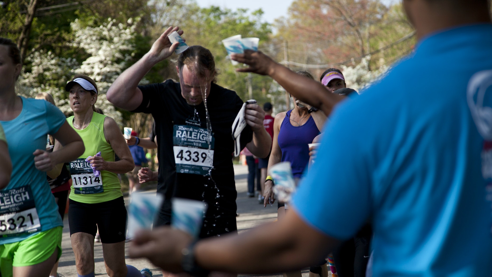 Fred Henninger Jr. pours water over his head at the mile 12 water station in Raleigh, NC during the Raleigh Rock 'n' Roll Marathon & Half Marathon, Sunday, April 13, 2014. Authorities say two runners have died near the finish line of the half marathon.