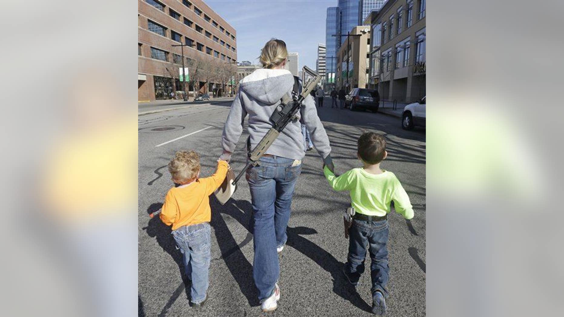 Gun rights activist Siri Davidson, center, has her AR15 slung on her back, as she walks with her children Keaton, 2, and Porter, 5, during a march for the 2nd Amendment rights Saturday, March 2, 2013, in Salt Lake City.